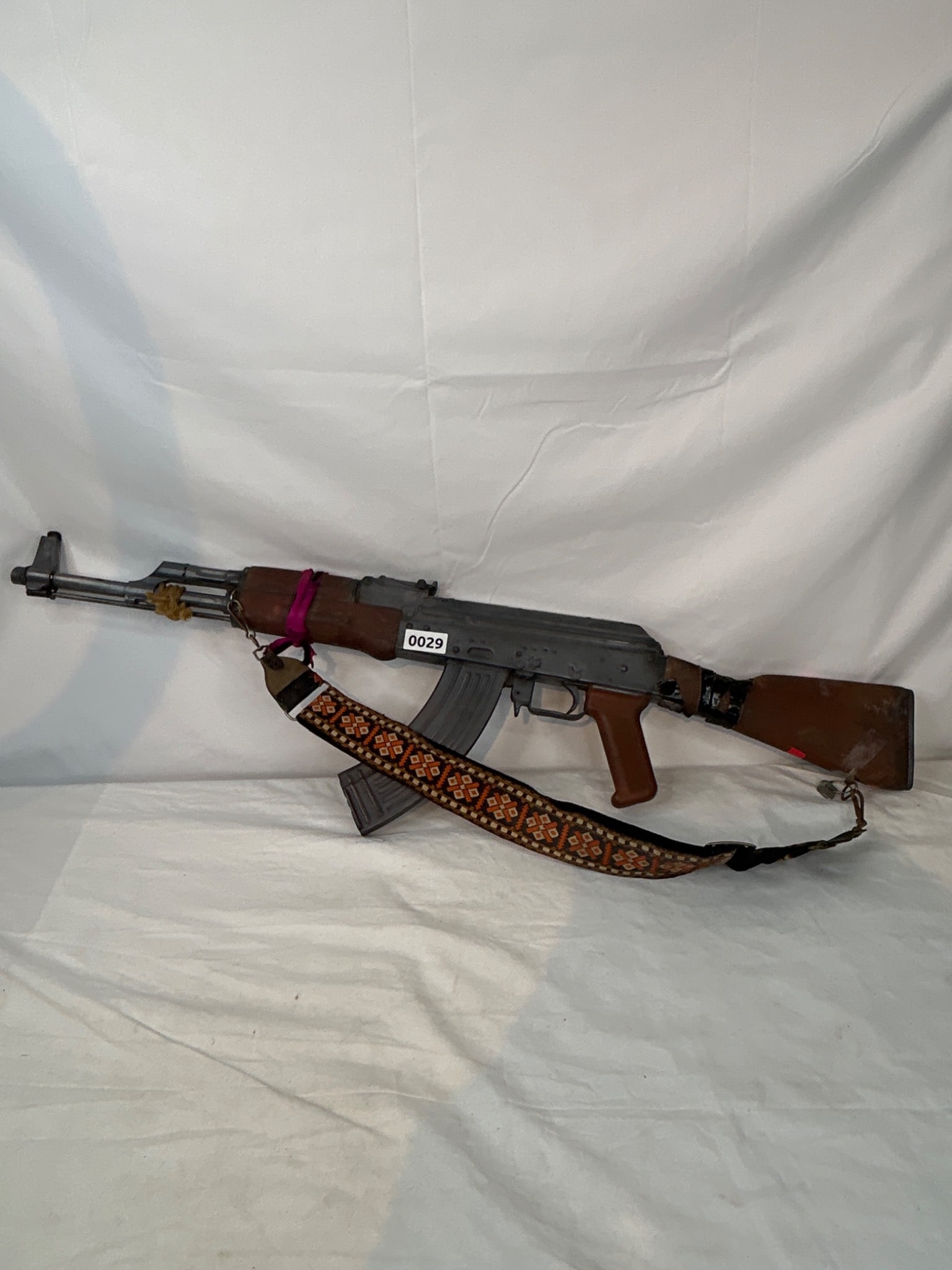 Replica AK-47-Style Display Model: A replica AK-47 rifle with wood and metal construction, featuring Arabic script detailing. Decorative sling included. Offered as is where is.The only lots that we in-house pack and ship are firearms.