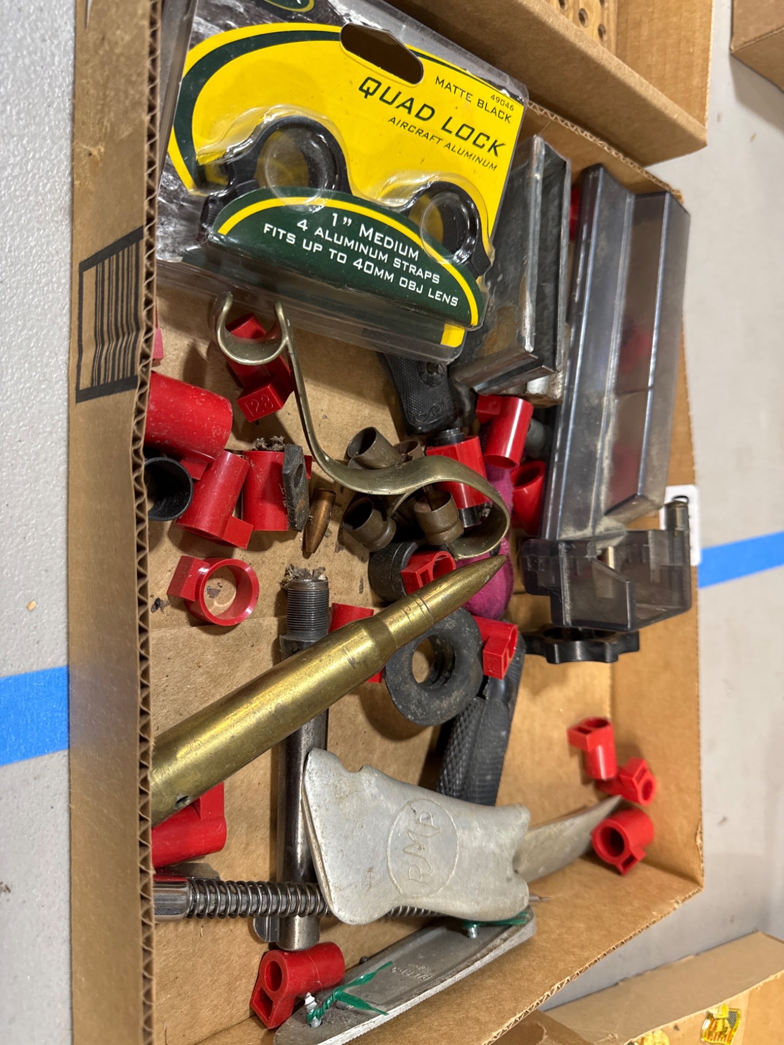 Gun Parts and Reloading Items: Box containing assorted gun parts and reloading items, including Quad Lock ring mounts, brass components, grips, and various reload-related tools. All items are sold AS IS, WHERE IS with no warranties