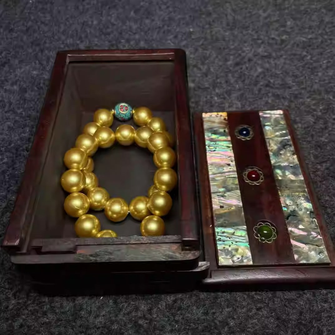 A rosewood box inlaid with mother-of-pearl contains a precious pearl bracelet: Bracelet dimensions: 14 mm in diameter, Jewelry box dimensions: 14/8/6 cm (L/W/H).
