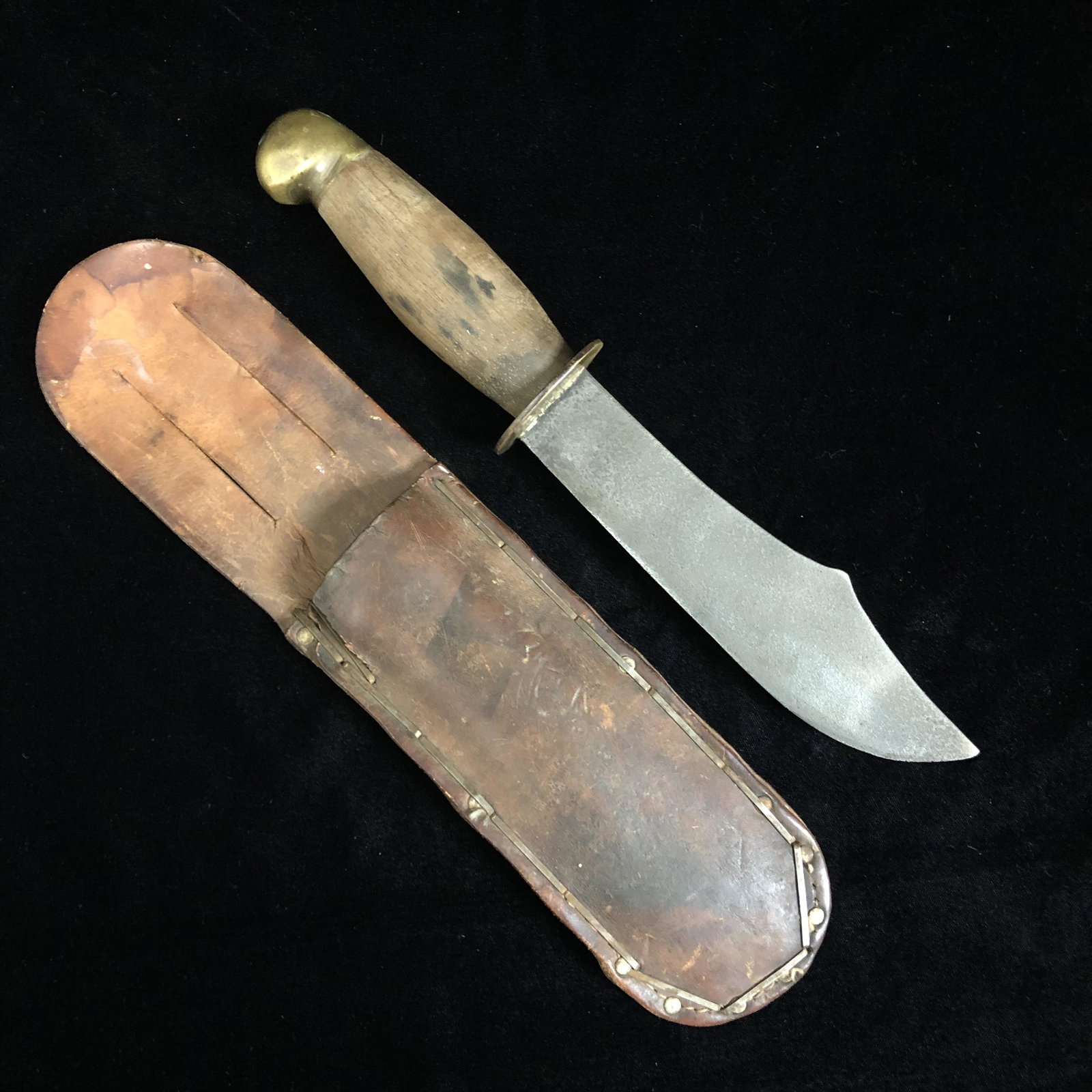 WWII Theater Made Trench Art Knife and Sheath: WWII theater made fixed blade trench art fighting knife in leather sheath. Solid carbon steel blade, scrap brass guard and pommel, and wood grip. Knife is solid. Blade is mildly pitted.