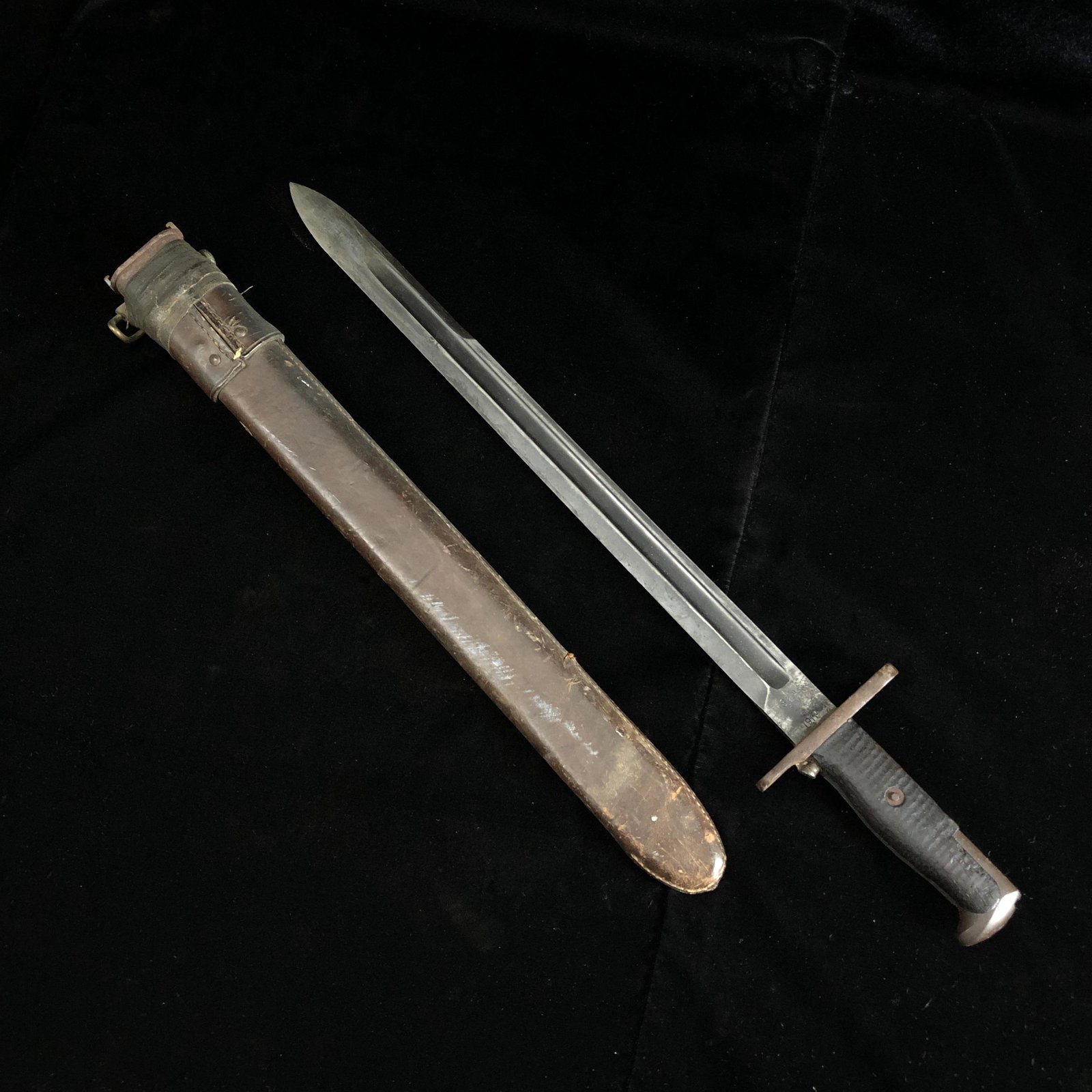 M1 Garand Bayonet 16" S.A. 1911 in RIA 1907 Scabbard: WWI 1911 US M1 Garand bayonet numbered 476976. Wood grips. Locking pin works. Blade in good shape. In leather wrapped scabbard made by Rock Island Arsenal, dated 1907. Appears to be initialed E.E.B. L