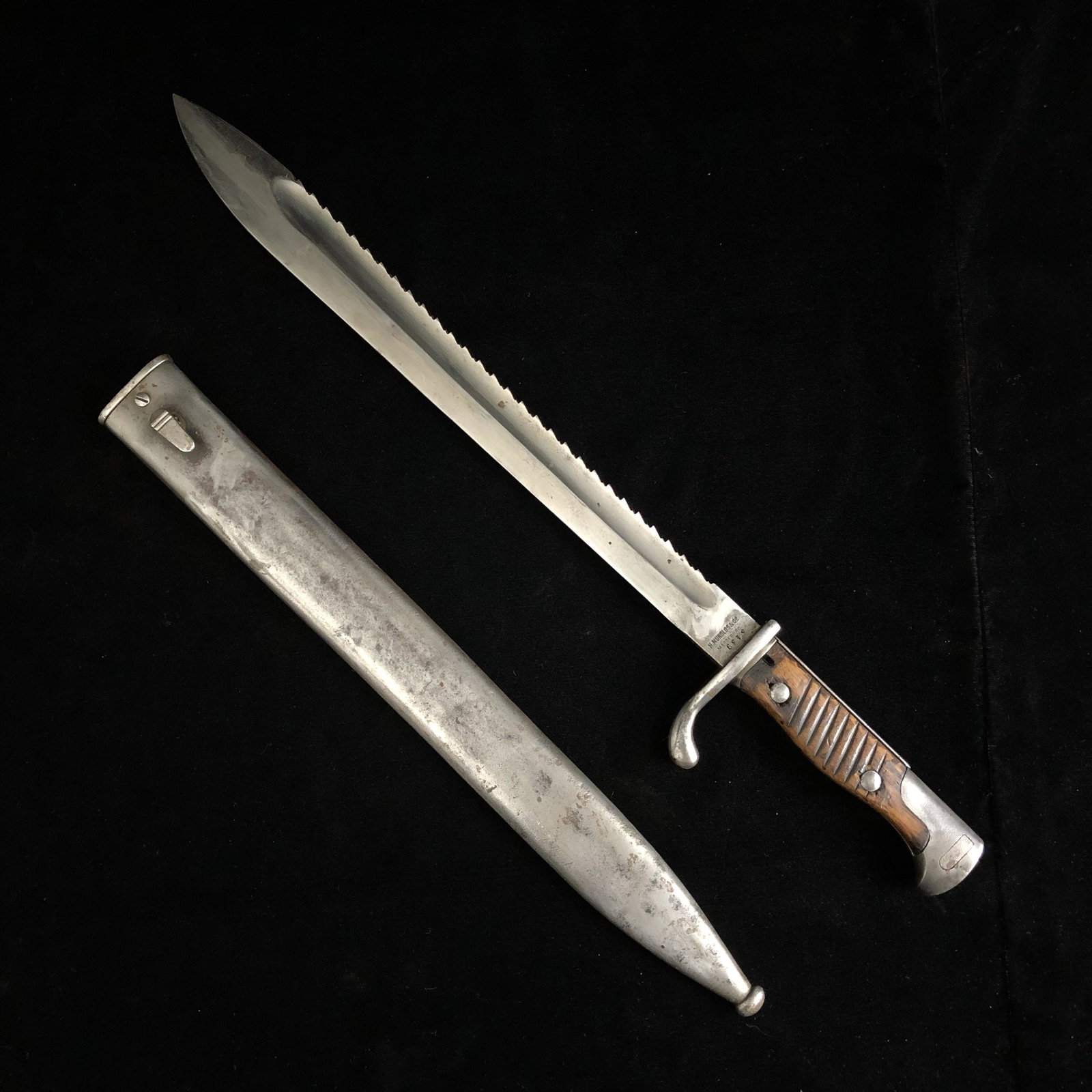 WWI Imperial German Sawtooth Sawback Butcher Bayonet: WWI imperial German sawback sawtooth butcher blade bayonet date has been removed made by H. Mundlos & Co. number 3439 in original metal scabbard. Locking pin works. Grips solid. Knife and scabbard in 