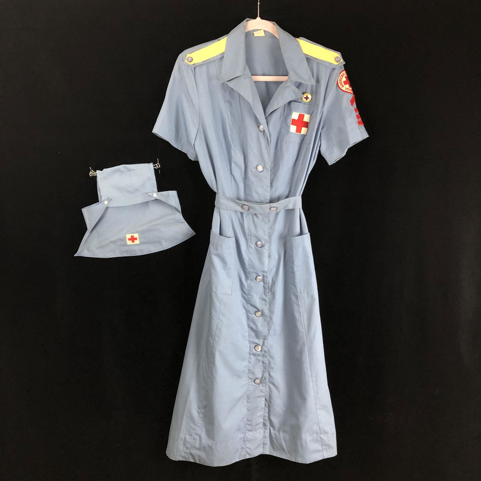 WWII Red Cross Dress - Blue Volunteer Woman's Dress & Hat: WWII era blue and white Red Cross woman's volunteer uniform with patches and enamel pin. Blue opalescent buttons are all present. no significant holes, or tears. Comes with matching hat. Measurements: