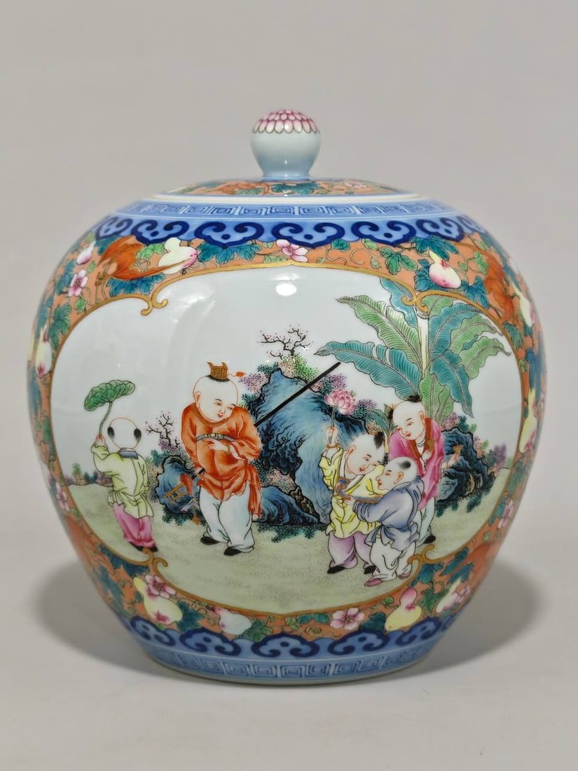 A famille rose covered jar with a bat and gourd design and children playing in a window: A famille rose covered jar with a bat and gourd design and children playing in a window, bearing the mark of the Qianlong period of the Qing Dynasty. It measures 19.5 cm in height and 18 cm in diamete