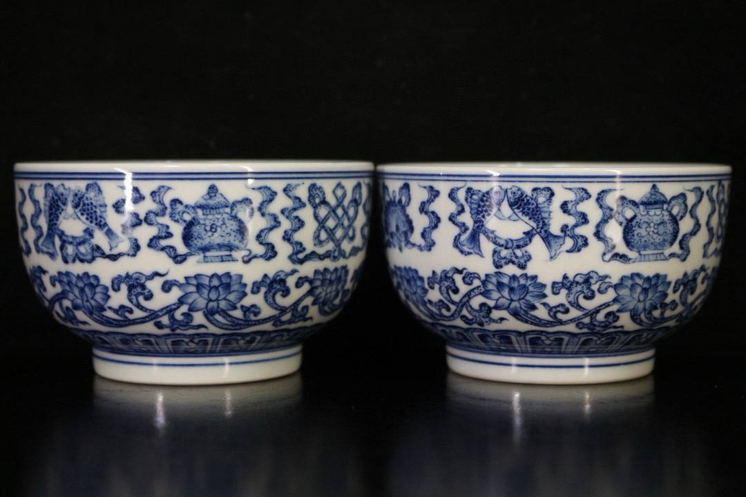 A pair of Qing dynasty blue and white porcelain cups with lotus scroll and eight auspicious symbols.: A pair of Qing dynasty blue and white porcelain cups with lotus scroll and eight auspicious symbols. Width: 9.6 cm; Height: 5.6 cm.