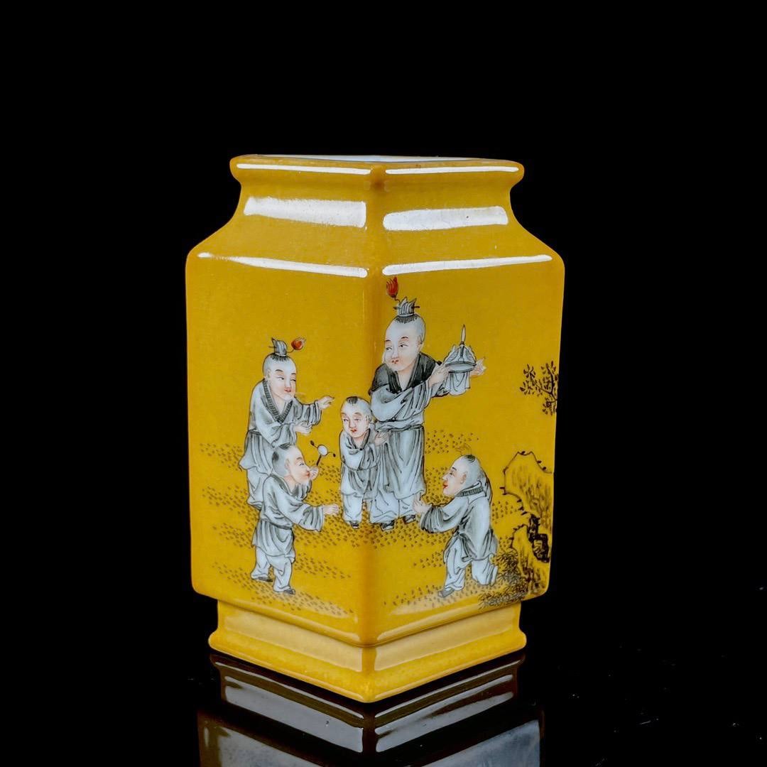 A square vase with a yellow glaze and ink-painted design of children at play: A square vase with a yellow glaze and ink-painted design of children at play, made during the Qianlong reign. Height: 11 cm; Width: 8.5 cm.