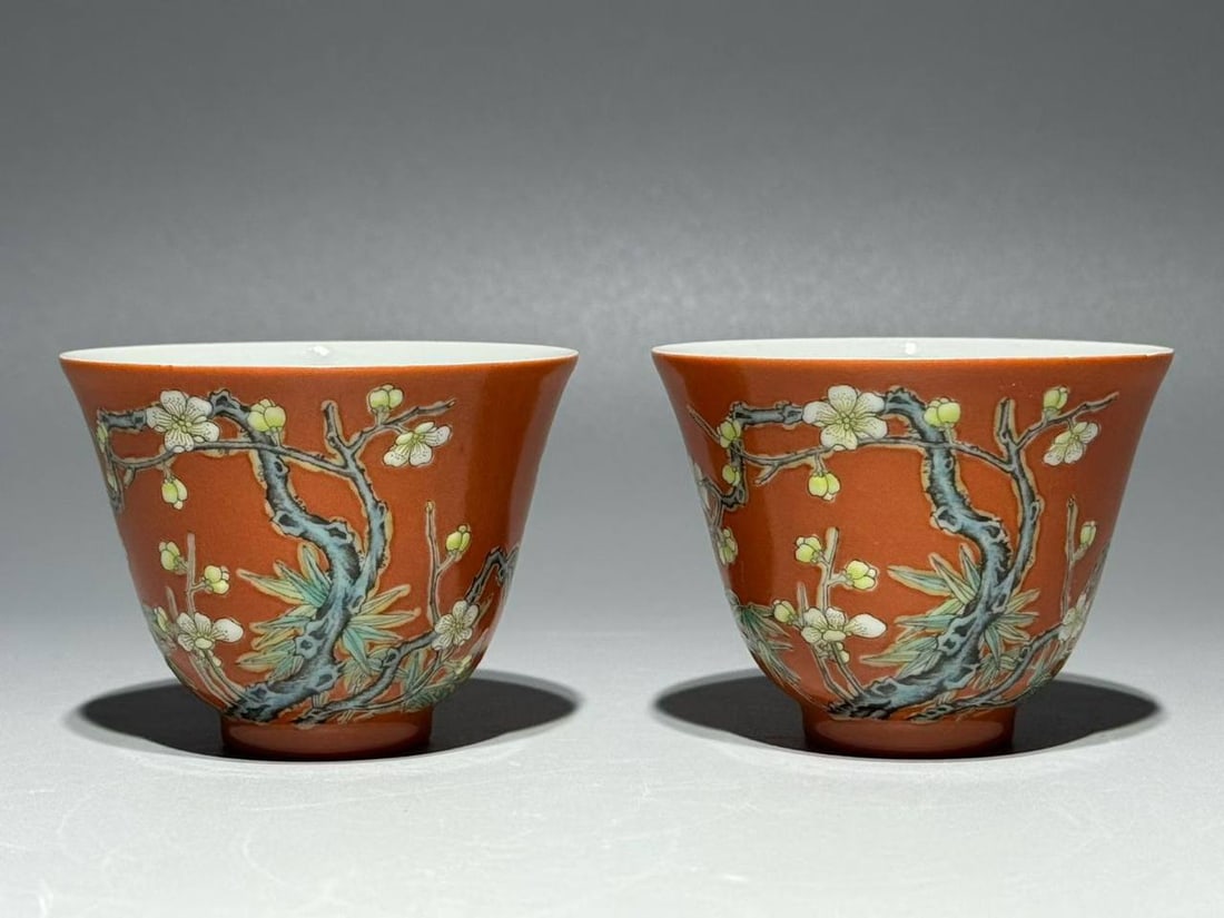 A Qing Dynasty Yongzheng period famille rose cups with a design of plum blossoms: A Qing Dynasty Yongzheng period famille rose cups with a design of plum blossoms and bamboo vying for spring on a red ground. Height: 5.4cm, Width: 7cm