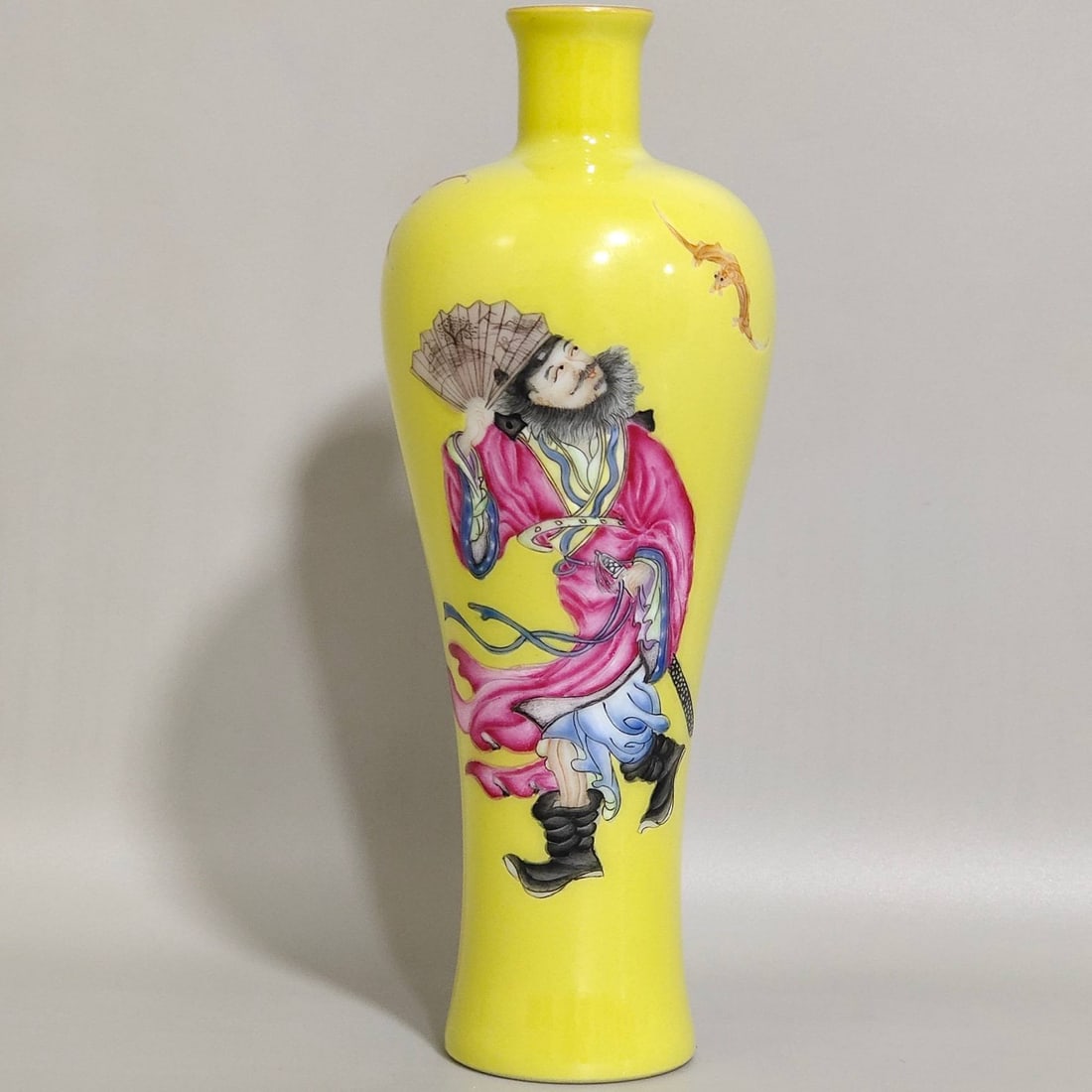 A Qing Dynasty Yongzheng period lemon-yellow glazed plum vase: A Qing Dynasty Yongzheng period lemon-yellow glazed plum vase with figures depicting the theme of "Good Fortune Before Your Eyes," 15 cm high and 5.5 cm in diameter.