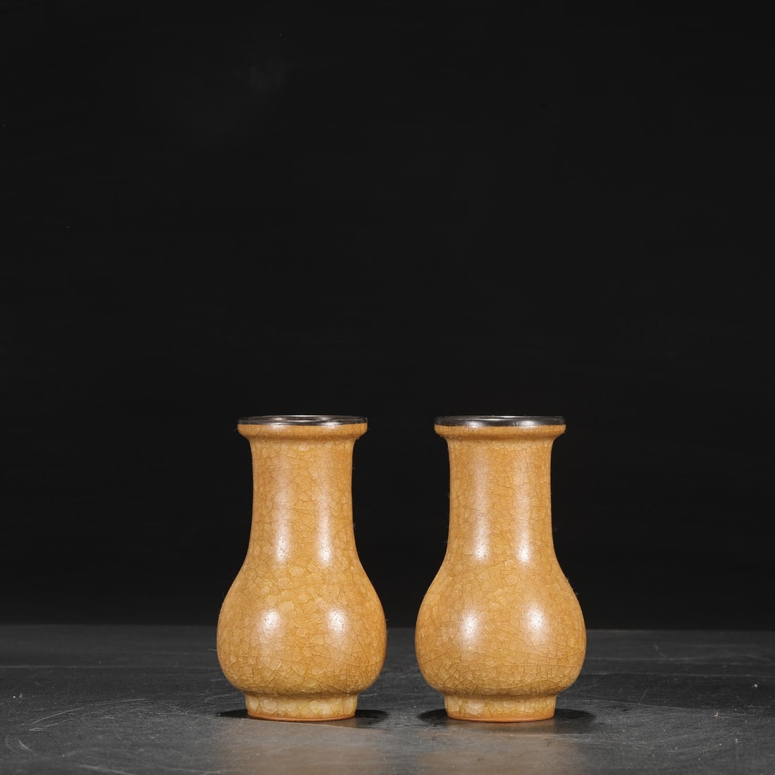 A pair of Southern Song Dynasty official kiln beige-glazed silver-rimmed vases with ice-crack: Dimensions: Height 15.5 cm, Mouth Diameter 6.5 cm, Belly Diameter 8.5 cm.
