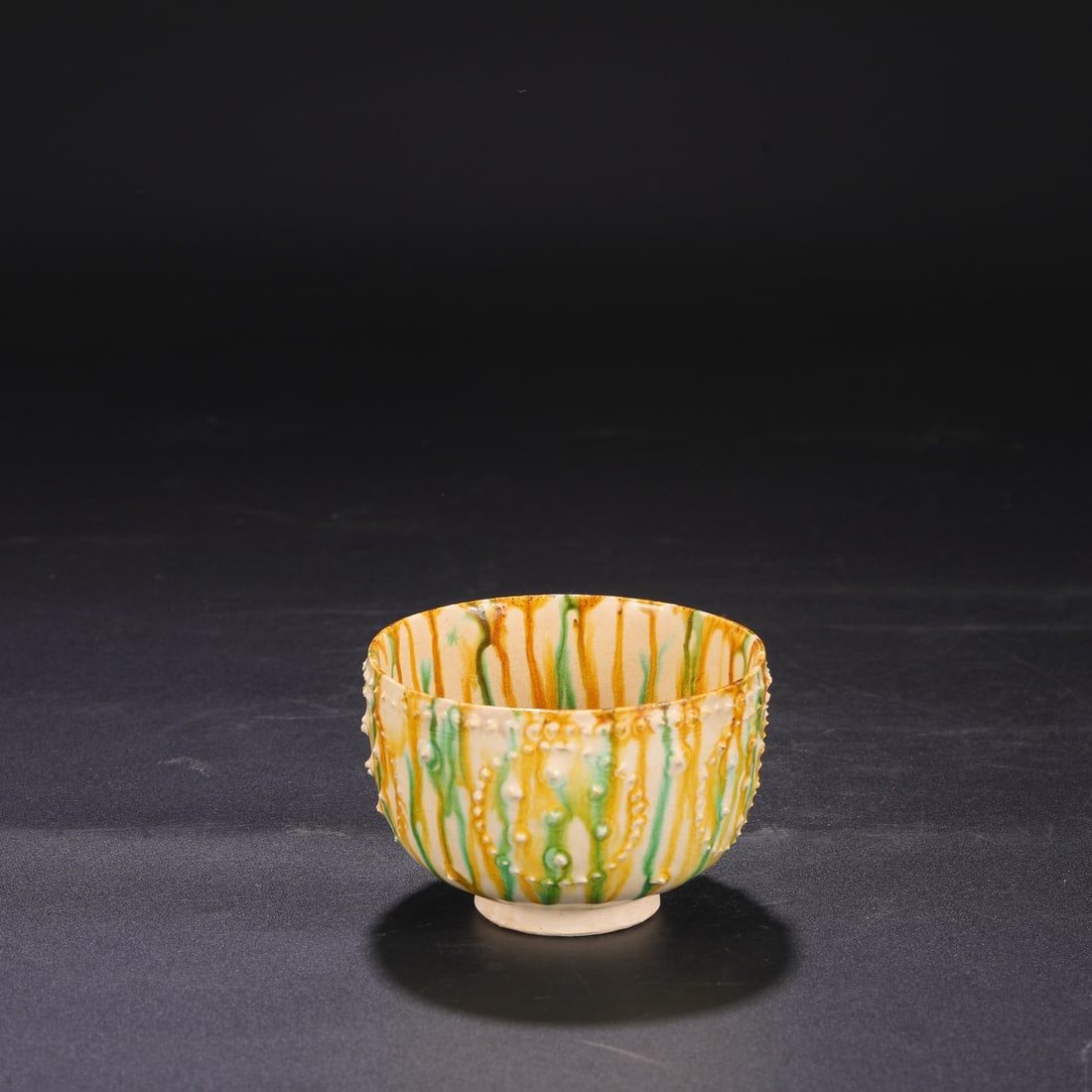 A Tang Dynasty Gongxian kiln sancai (three-color glazed) bowl with drum-nail design, formerly in the: Dimensions: Height 7.5 cm, Diameter 10.5 cm.