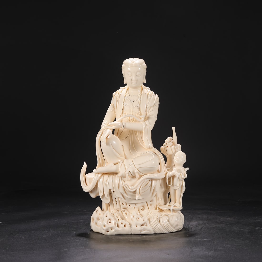 A Ming Dynasty Dehua kiln ivory-yellow glazed seated statue of a child worshipping Guanyin. (1 of 8)