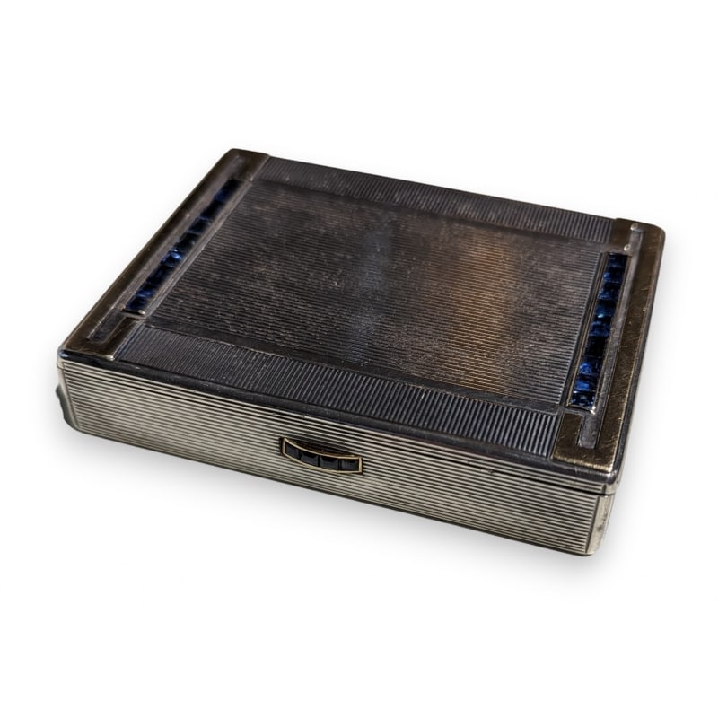 French 20th century 800 silver powder box by Charles Holl: A rectangular 800 silver powder compact, the exterior striated and decorated with a gilt geometric motif set with calibrated sapphires, also on the push button.Numbered 800/1000 and 64560 and marked "