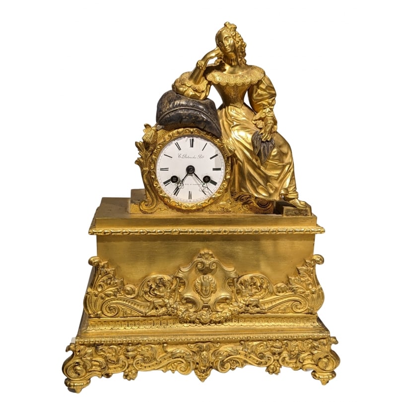 19th century Elegant Empire Court Clock in Gilt Bronze: An Empire-style gilt bronze clock with two patinas, depicting a young and elegant woman in a superb lace dress, leaning on a cushion with a silvered bronze patina. The cushion rests on a wire-driven m