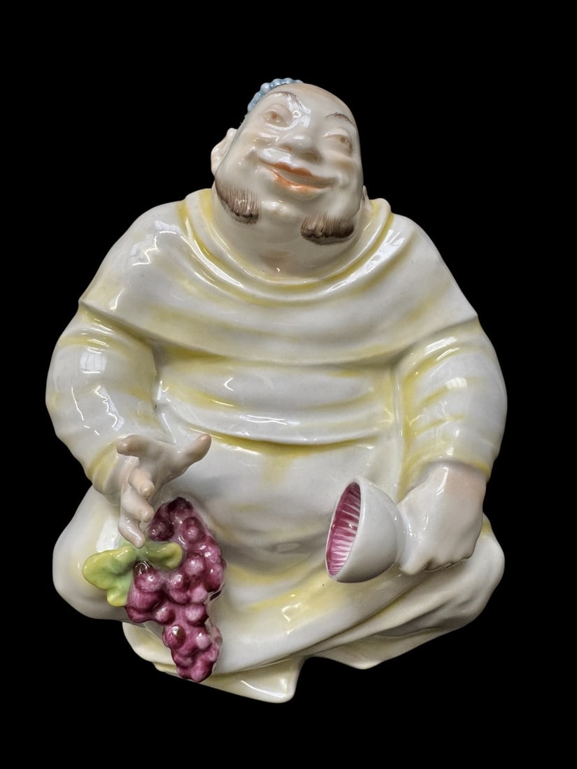 Volkstedt - Porcelain figure of a smiling monk by Emil Paul Börner: A Volkstedt porcelain figurine depicting a smiling monk holding a chalice of wine and grapes. This model was created by Emil Paul Börner, one of the most versatile and prolific artists at the Meissen