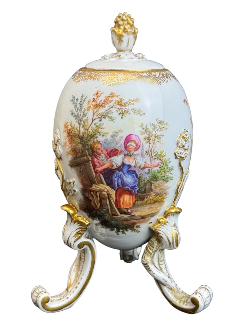 Meissen Porcelain Box: Meissen porcelain egg-shaped box on three rocaille feet. Decorated with flowers, gilding, and three scenes with beautifully painted figures. The lid is also very finely gilded. Blue sword mark on the