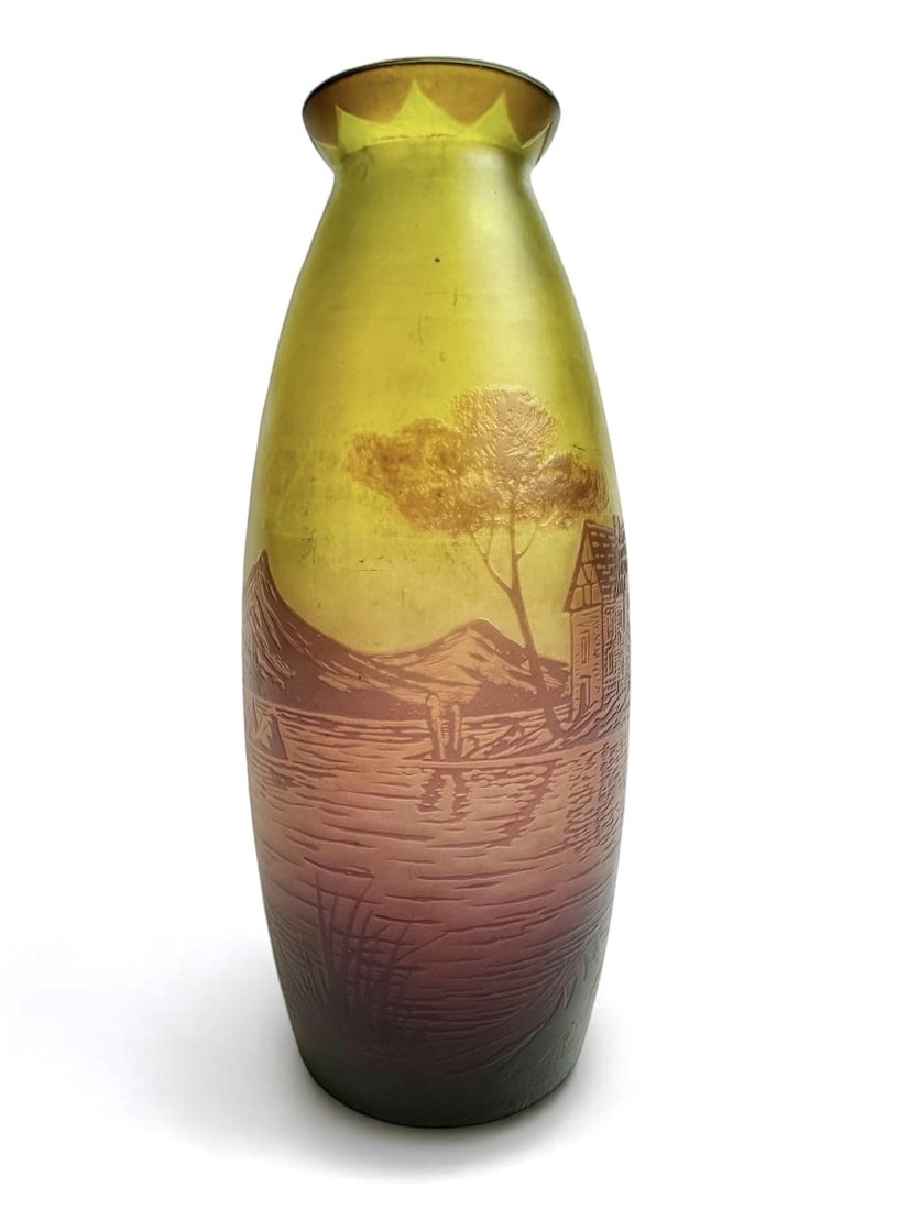 Degué Vase With Lake Landscape Decor: Multi-layered acid-etched vase in shades of yellow, ochre, and mauve, decorated with a lakeside landscape featuring a cabin, mountains in the background, and trees in the foreground. Signed Degué (Da