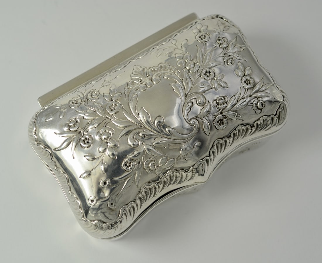 Silver box, Louis XVI style, France, late 19th century: A rectangular silver box with a flat base, rounded corners, and three curved sides. It is decorated around its entire circumference with bouquets of flowers tied in knots known as "Marie Antoinette kn