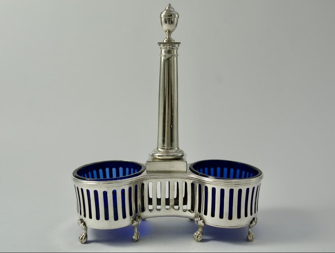 Double Salt Cellar in Silver and Blue Crystal, France, Circa 1787: Double salt cellar with openwork arcade decoration, the handle in the form of a column terminating in a vase. The containers are made of blue crystal and are original. Claw feet adorned with acanthus