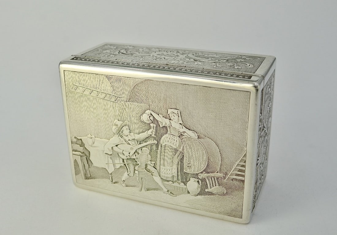 Silver Cigarillo Box, France, Circa 1914: A rectangular silver cigarillo box with a wooden core. The guilloché and engraved lid depicts a tavern scene, while the four sides are decorated with acid-etched floral and foliate scrolls.France, ea