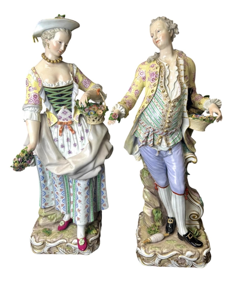 Large Meissen porcelain figurines depicting a couple of gardeners: The young woman in a summer dress and hat stands on a square, naturalistic-style base decorated with rocaille motifs in relief. She holds a wreath of flowers in her right hand and a basket of flowers