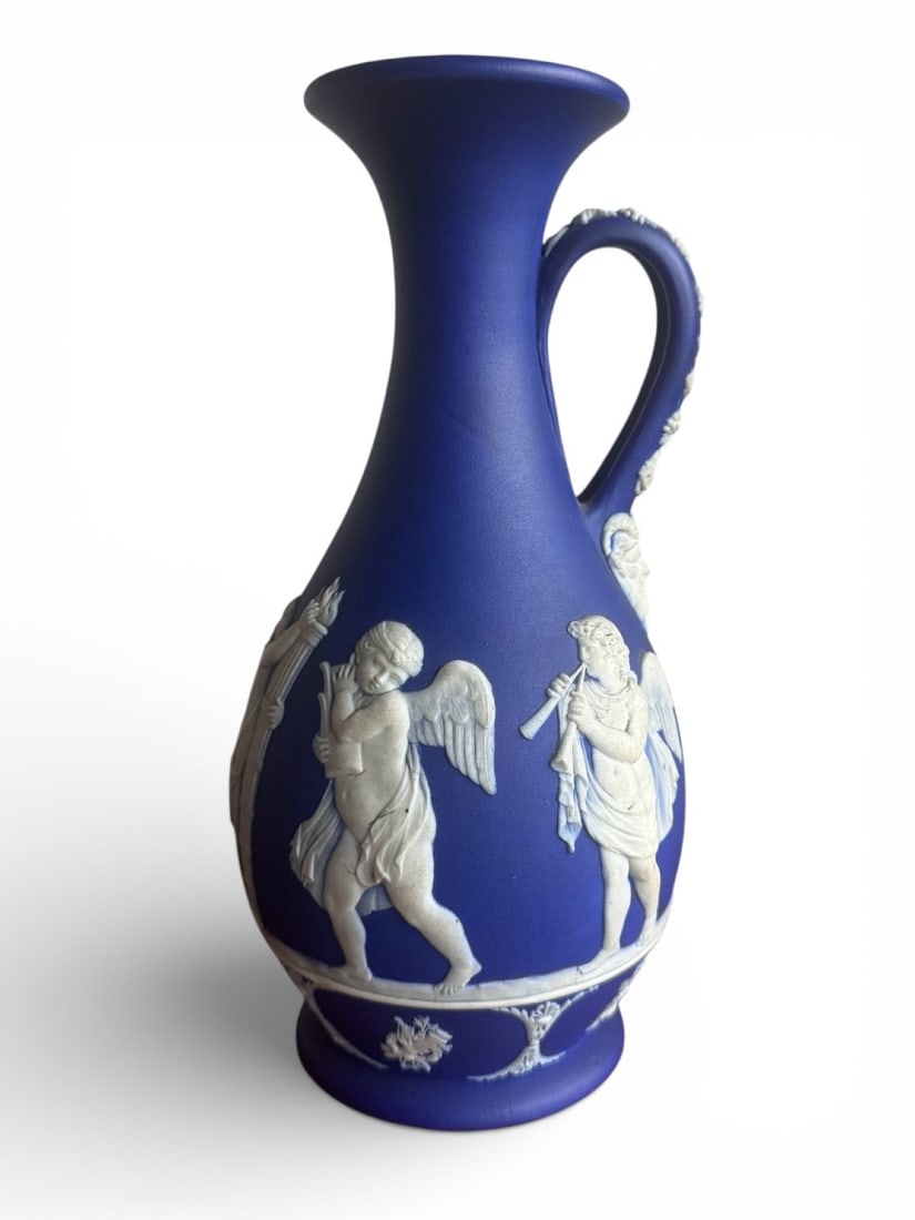 Wedgwood - Jasper Pitcher, 19th century: A blue and white jasper pitcher decorated with an extremely delicate application of white paste in neoclassical motifs of cupids playing music, laurel wreaths on the neck, vine tendrils on the handle,