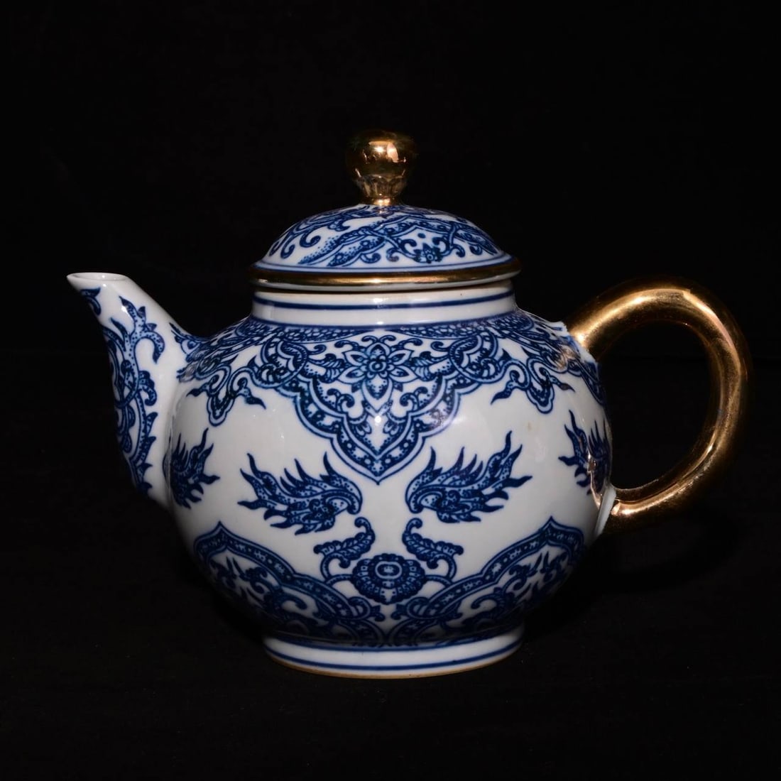 A blue-and-white porcelain teapot with gilt taotie design, made during the Qianlong period: A blue-and-white porcelain teapot with gilt taotie design, made during the Qianlong period of the Qing dynasty, measuring 13 x 16.5 cm in height.