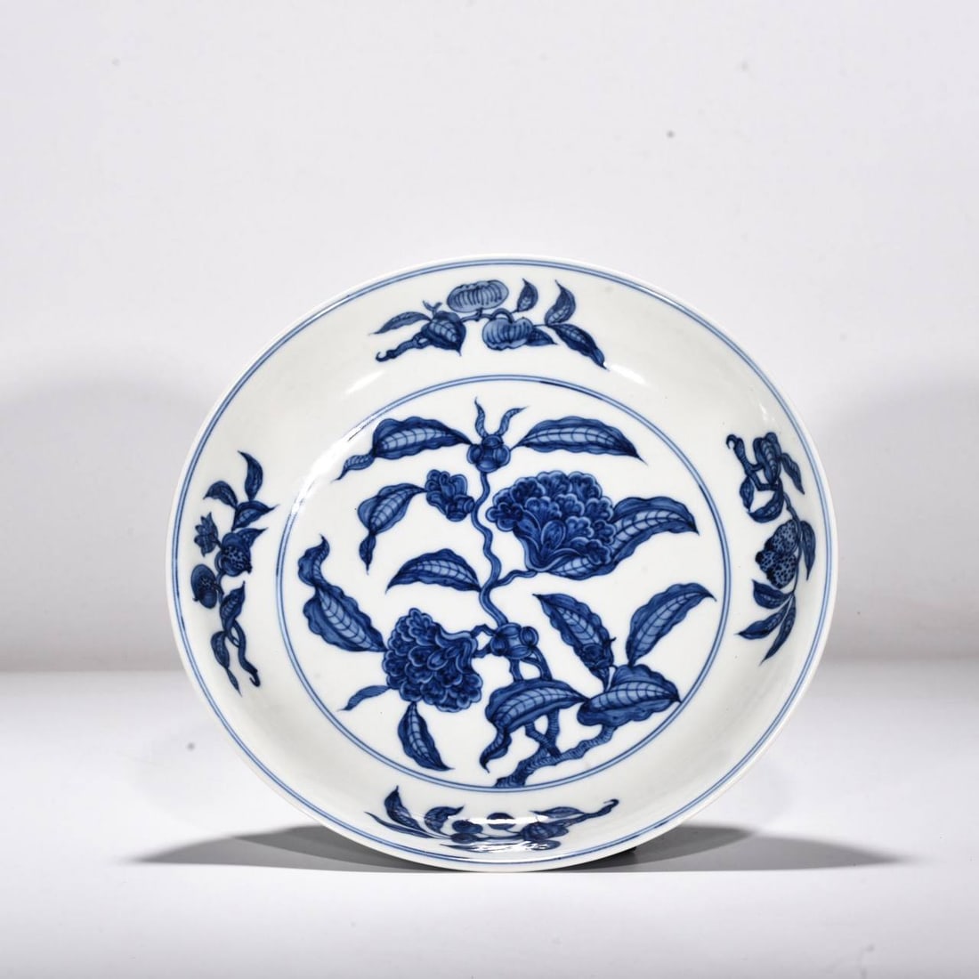 A Qing Dynasty Yongzheng period plate with a design: A Qing Dynasty Yongzheng period plate with a design of flowering branches and fruits. Height: 5.5 cm; Width: 28.5 cm.