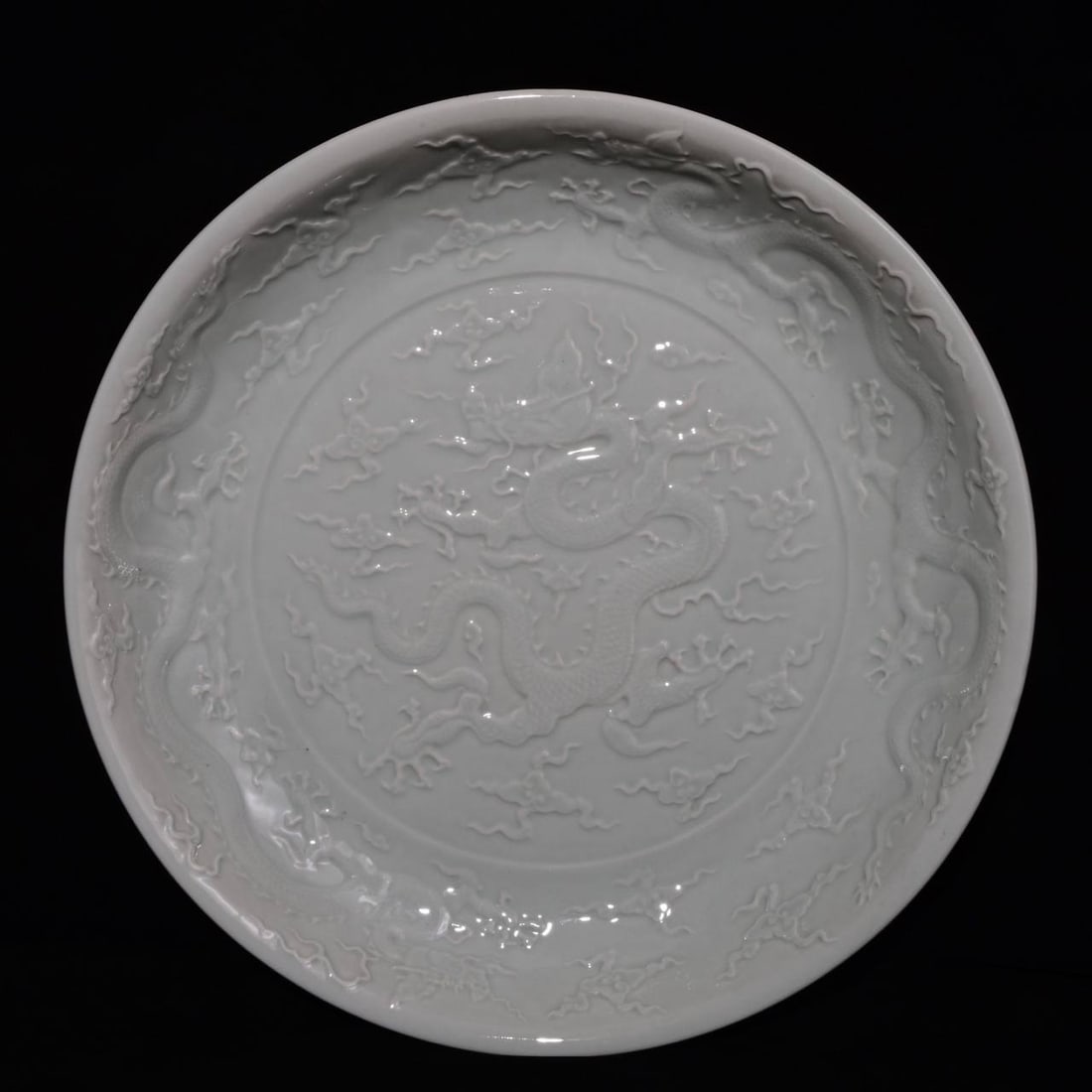 A white-glazed, carved dragon-patterned plate made during the Xuande reign of the Ming Dynasty,: A white-glazed, carved dragon-patterned plate made during the Xuande reign of the Ming Dynasty, measuring 7 x 44.8 cm in height.