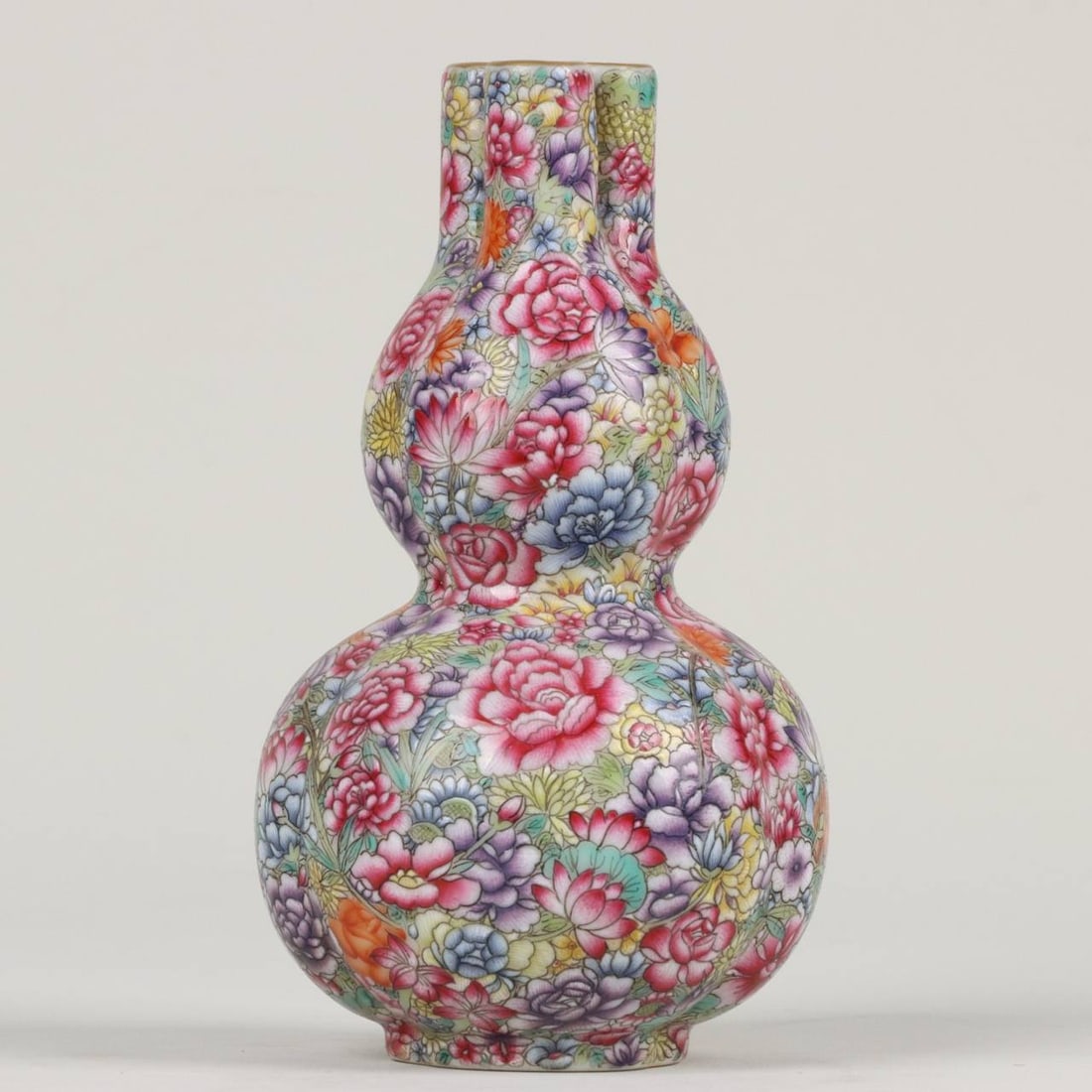 A Qianlong period (1736-1745) enamel-painted and gilt-decorated gourd-shaped vase: A Qianlong period (1736-1745) enamel-painted and gilt-decorated gourd-shaped vase with a myriad of floral patterns. Height and width: 15.5 x 9 cm.