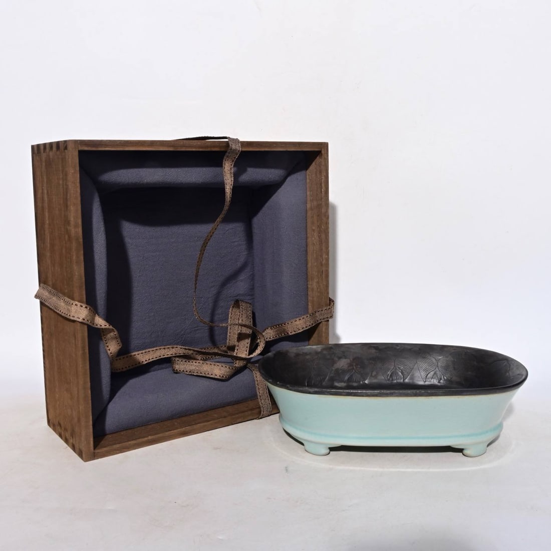 A Song Dynasty Ru ware narcissus basin with silver-wrapped chased dragon design: A Song Dynasty Ru ware narcissus basin with silver-wrapped chased dragon design, measuring 6.8 x 23.8 cm.