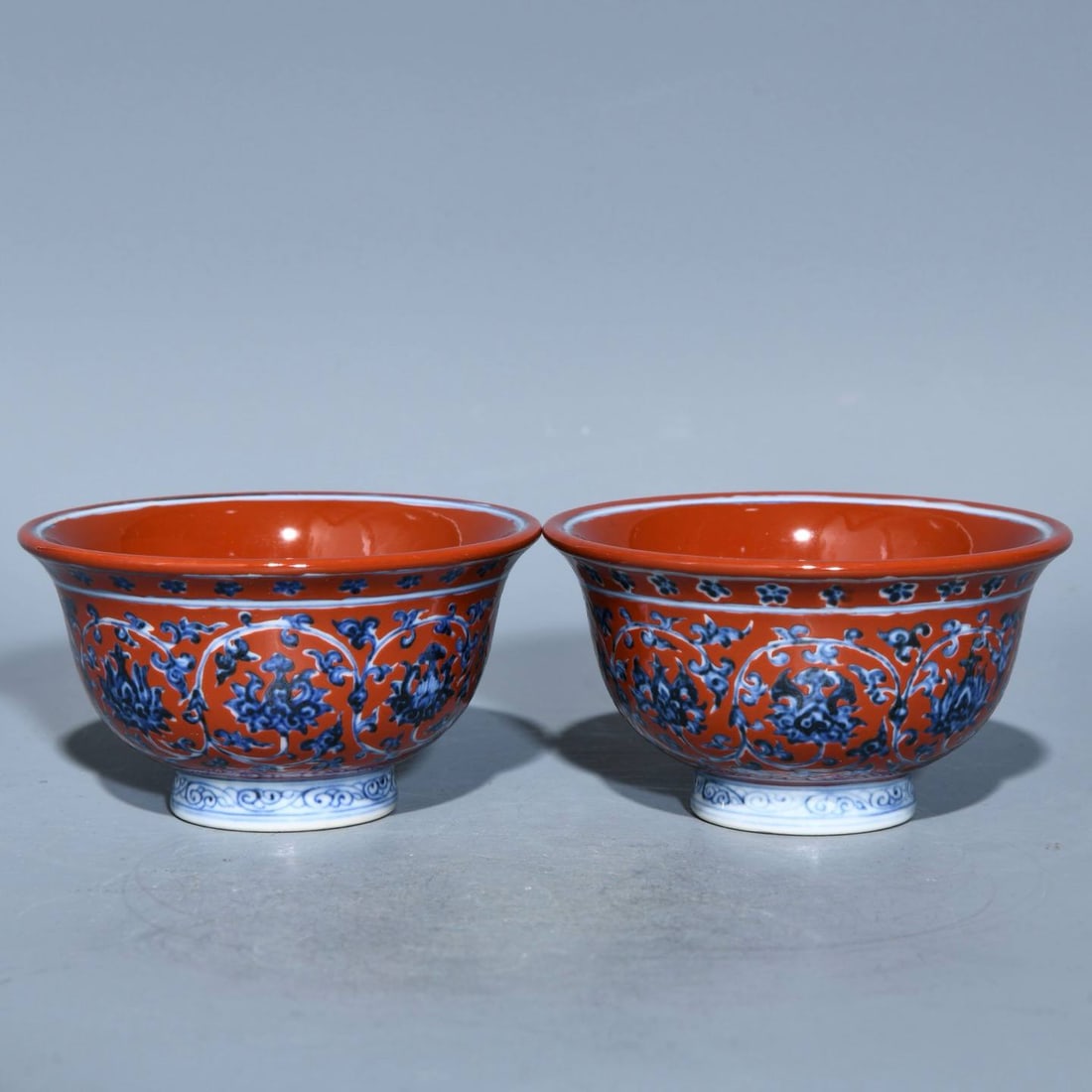 A Ming Dynasty Yongle period iron-red and blue-and-white lotus scroll design cups: A Ming Dynasty Yongle period iron-red and blue-and-white lotus scroll design cup, 5.4cm high and 9.5cm in diameter.