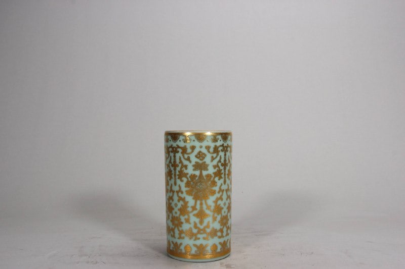 A celadon-glazed brush pot with gilt floral design from the Daoguang period of the Qing dynasty.: A celadon-glazed brush pot with gilt floral design from the Daoguang period of the Qing dynasty. Height: 12.8 cm; Mouth diameter: 7 cm.