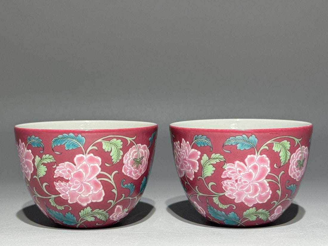 A Qing Dynasty Yongzheng period famille rose enamel cups: A Qing Dynasty Yongzheng period famille rose enamel cups with a rouge-red ground and a foot rim, decorated with scrolling floral patterns. Height: 5cm; Mouth diameter: 7.1cm.