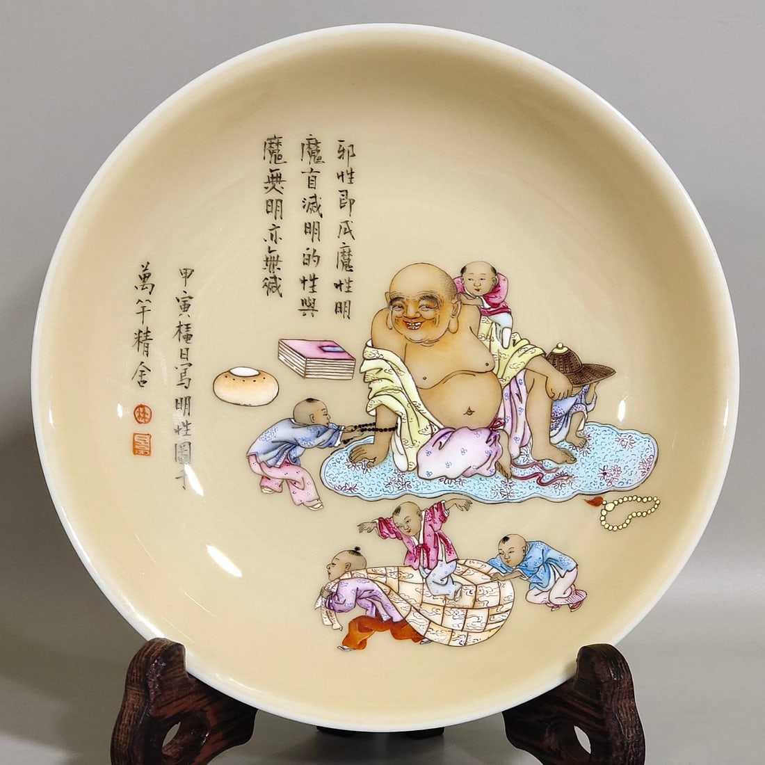 A Qing Dynasty (Yongzheng period) beige-glazed plate with a design of a monk and five children playi: A Qing Dynasty (Yongzheng period) beige-glazed plate with a design of a monk and five children playing, inscribed with a poem. 3 cm high, 14.1 cm in diameter.