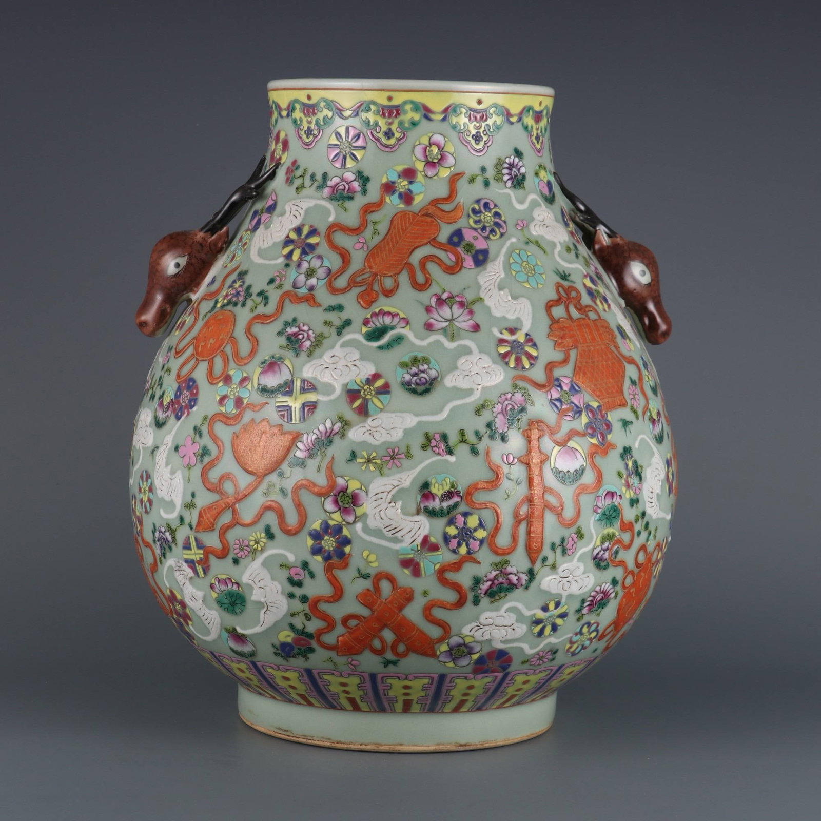 A celadon-glazed, carved and gilded famille rose vase: A celadon-glazed, carved and gilded famille rose vase with eight auspicious symbols and a deer head design, made during the Qianlong period of the Qing dynasty. Dimensions: Height 33.5 cm, Mouth Diame