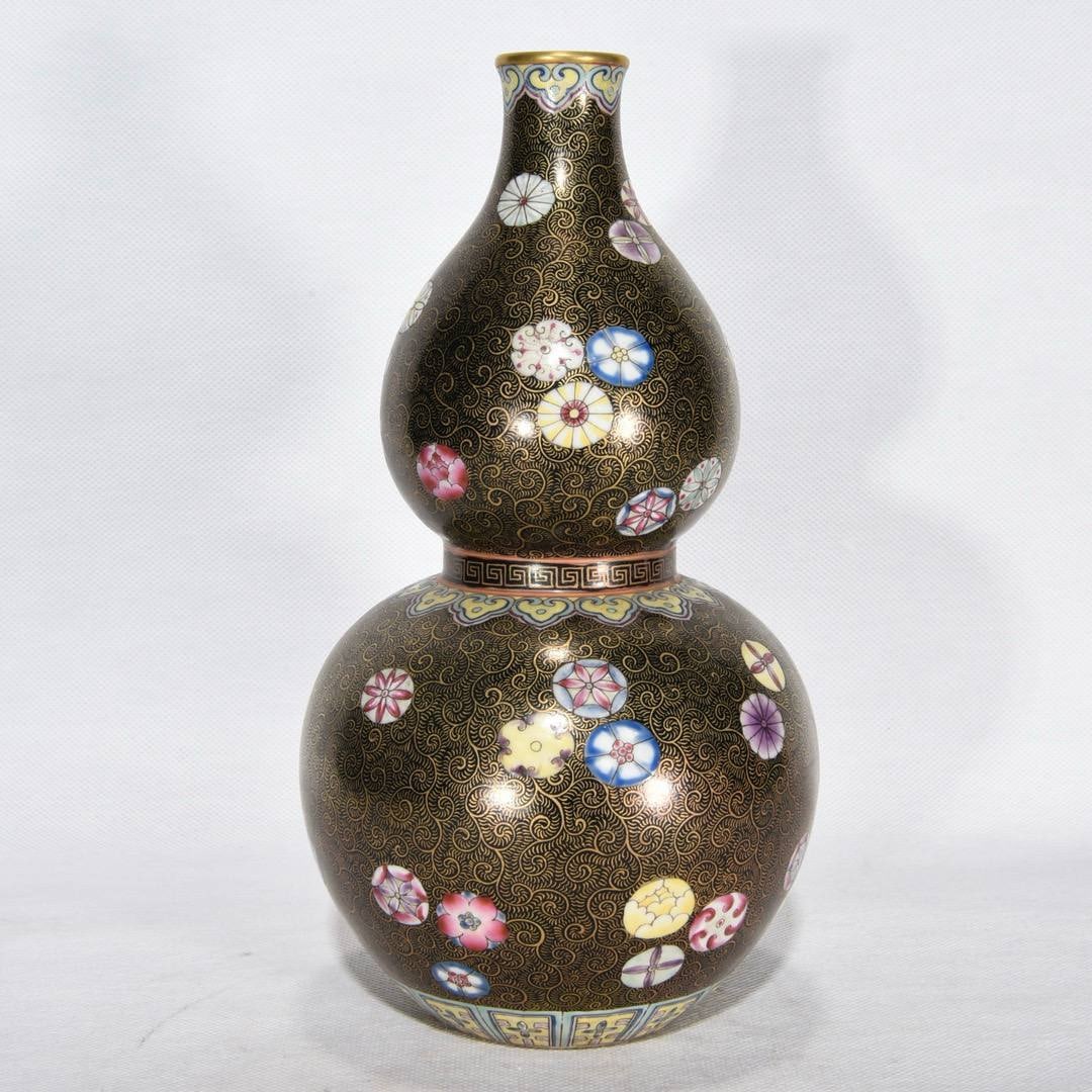 A Qing Dynasty Qianlong period: A Qing Dynasty Qianlong period famille rose enamel gourd-shaped vase with a ball and floral design, 22.5 x 12 cm.