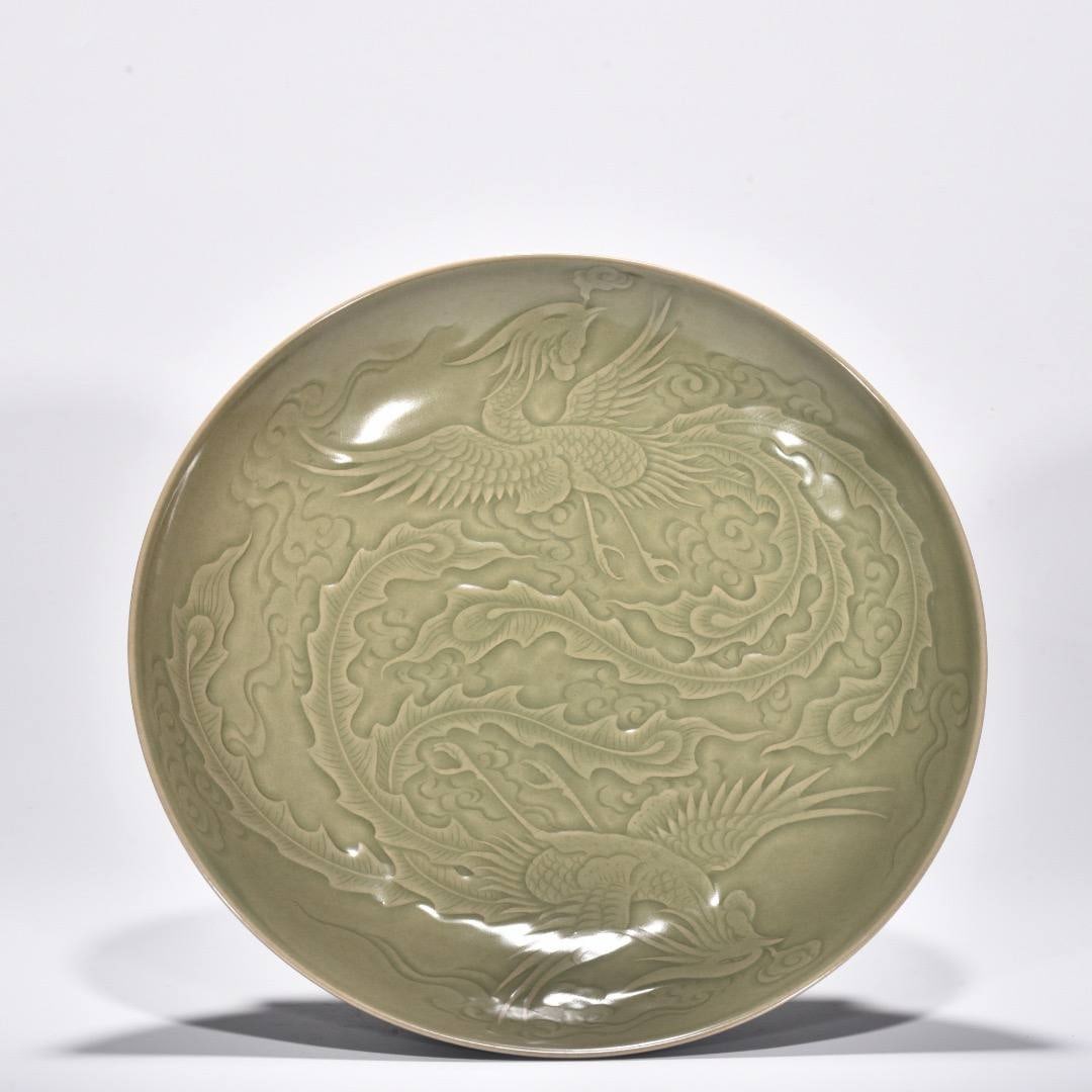 Large celadon plate with phoenix design: Large celadon plate with phoenix design from the Yue ware kiln, dating from the Five Dynasties period. Height: 6.1 cm; Width: 29.7 cm.