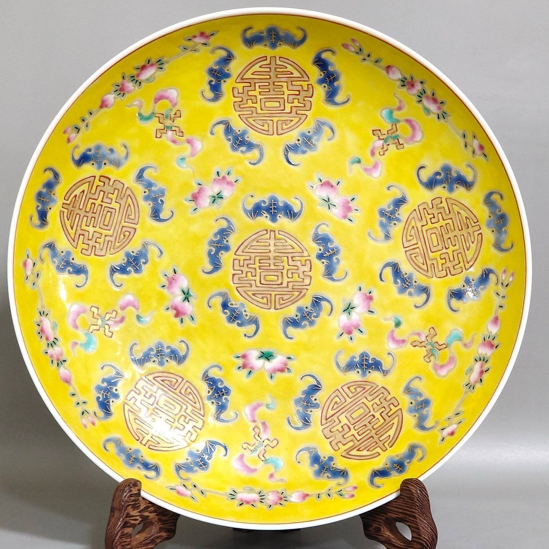 A yellow-glazed dish with five auspicious symbols and a longevity symbol: A yellow-glazed dish with five auspicious symbols and a longevity symbol, dating from the Tongzhi period of the Qing Dynasty. 4 cm high, 21 cm in diameter.