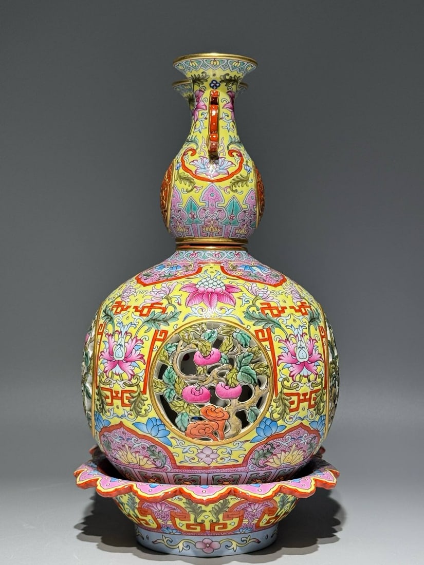 A Qing Dynasty Qianlong period (1736-1745) famille rose enamel vase: A Qing Dynasty Qianlong period (1736-1745) famille rose enamel vase with a yellow ground, featuring openwork design depicting auspicious symbols of good fortune and longevity, and a double-linked revo