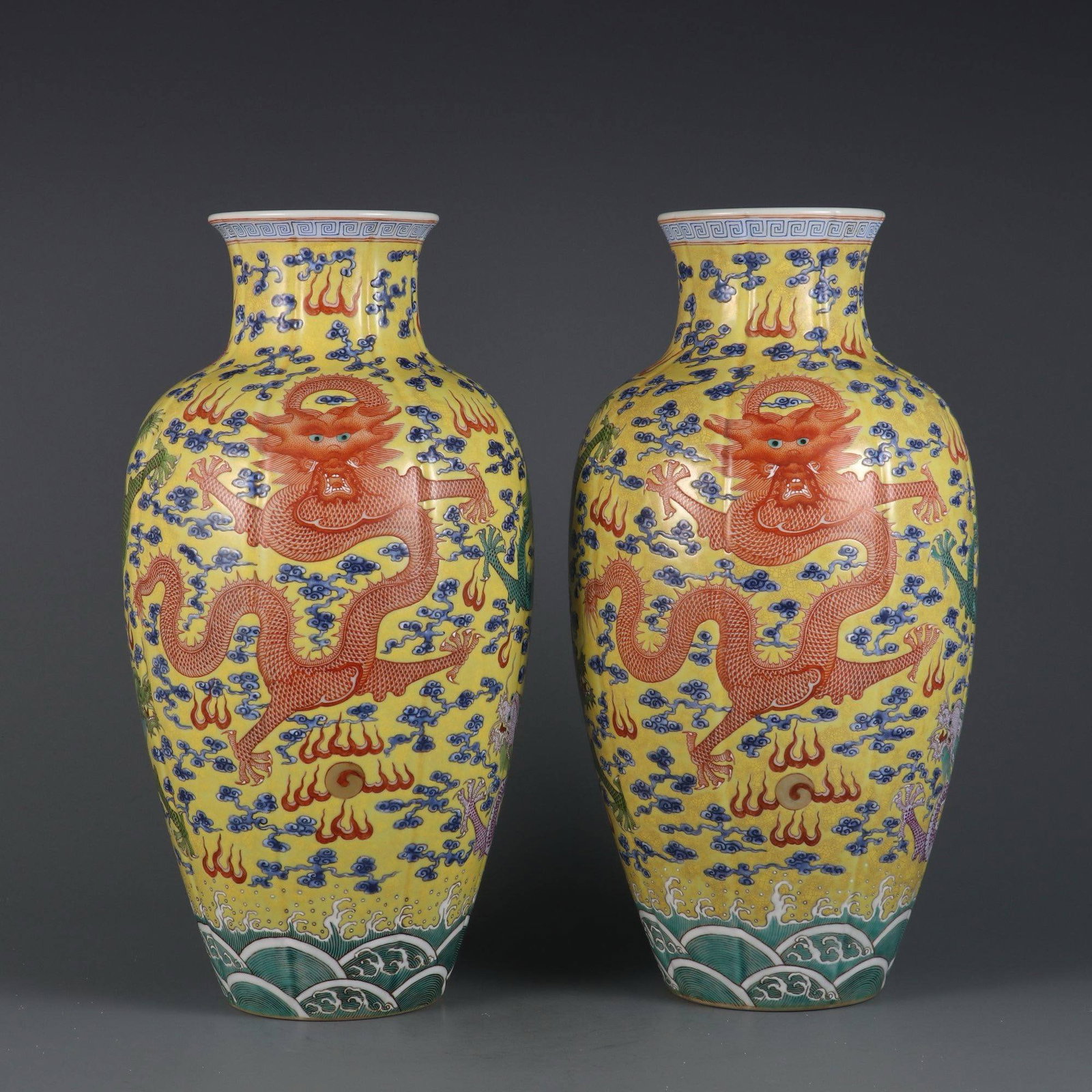 A pair of yellow-ground famille rose melon-shaped vases: A pair of yellow-ground famille rose melon-shaped vases with cloud and dragon design, made during the Yongzheng period of the Qing dynasty. Dimensions: Height 32.5 cm, Belly diameter 16 cm, Mouth diam