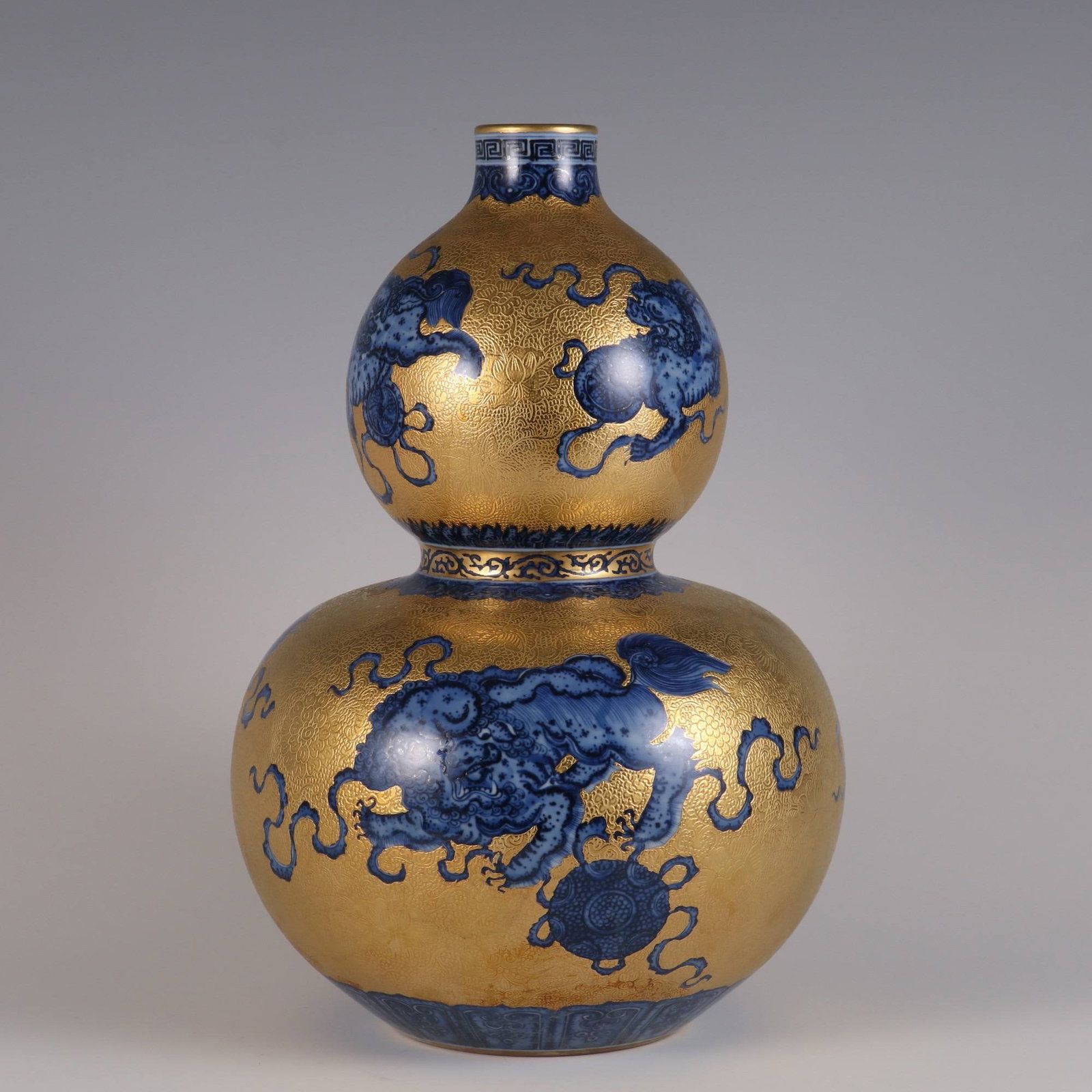 A Qing Dynasty Qianlong period (1736-1745) blue and white porcelain vase: A Qing Dynasty Qianlong period (1736-1745) blue and white porcelain vase with a lion and embroidered ball design on a gold ground. Dimensions: Height 31.2 cm, Belly diameter 20 cm, Mouth diameter 4 cm