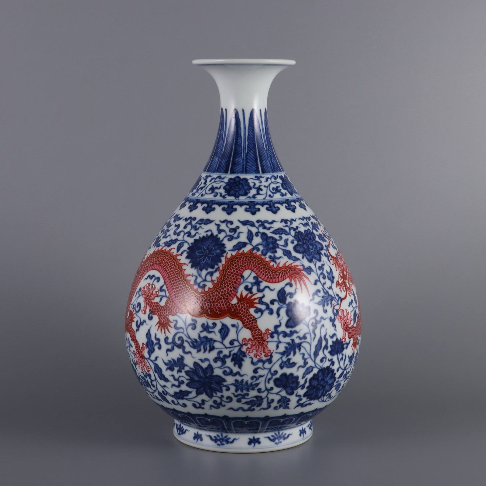 A Qing Dynasty Yongzheng period blue and white porcelain vase: A Qing Dynasty Yongzheng period blue and white porcelain vase with rouge-red enamels depicting dragons amidst lotus scrolls. Dimensions: Height 29.2 cm, Belly diameter 17.5 cm, Mouth diameter 7.6 cm.