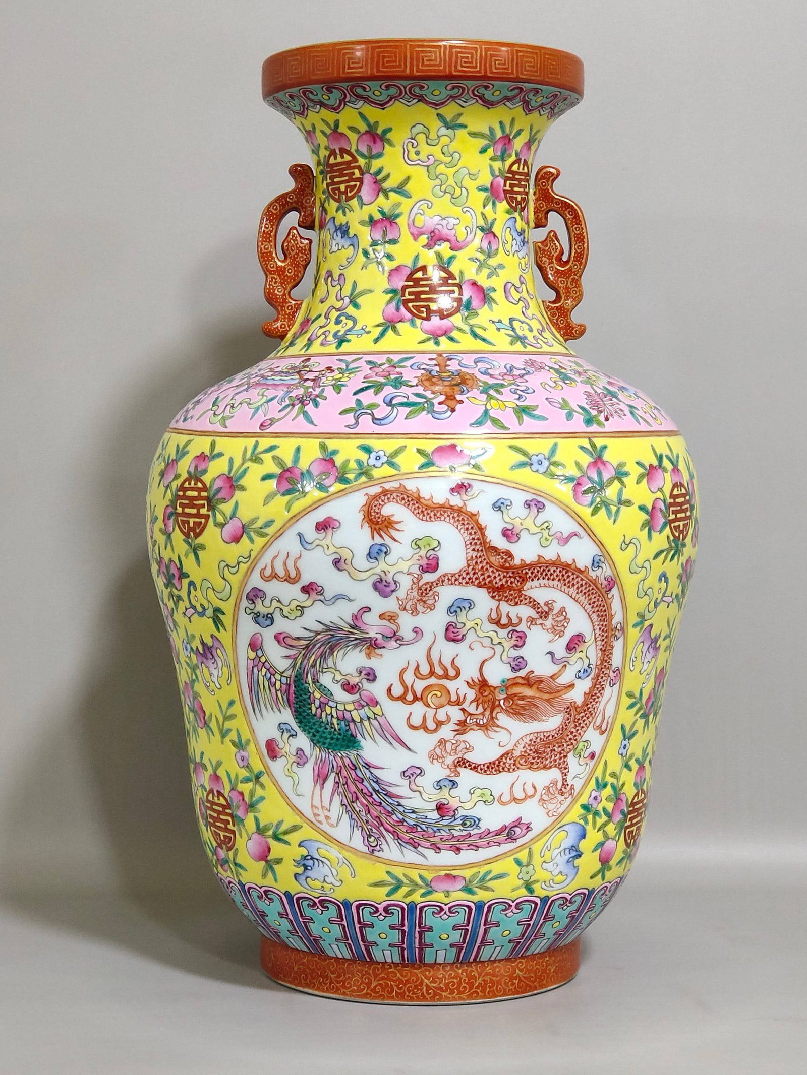 A Qing Dynasty Qianlong period yellow-ground vase: A Qing Dynasty Qianlong period yellow-ground vase with dragon and phoenix handles and auspicious motifs (representing longevity and good fortune), 32.5 cm high and 18 cm in diameter.
