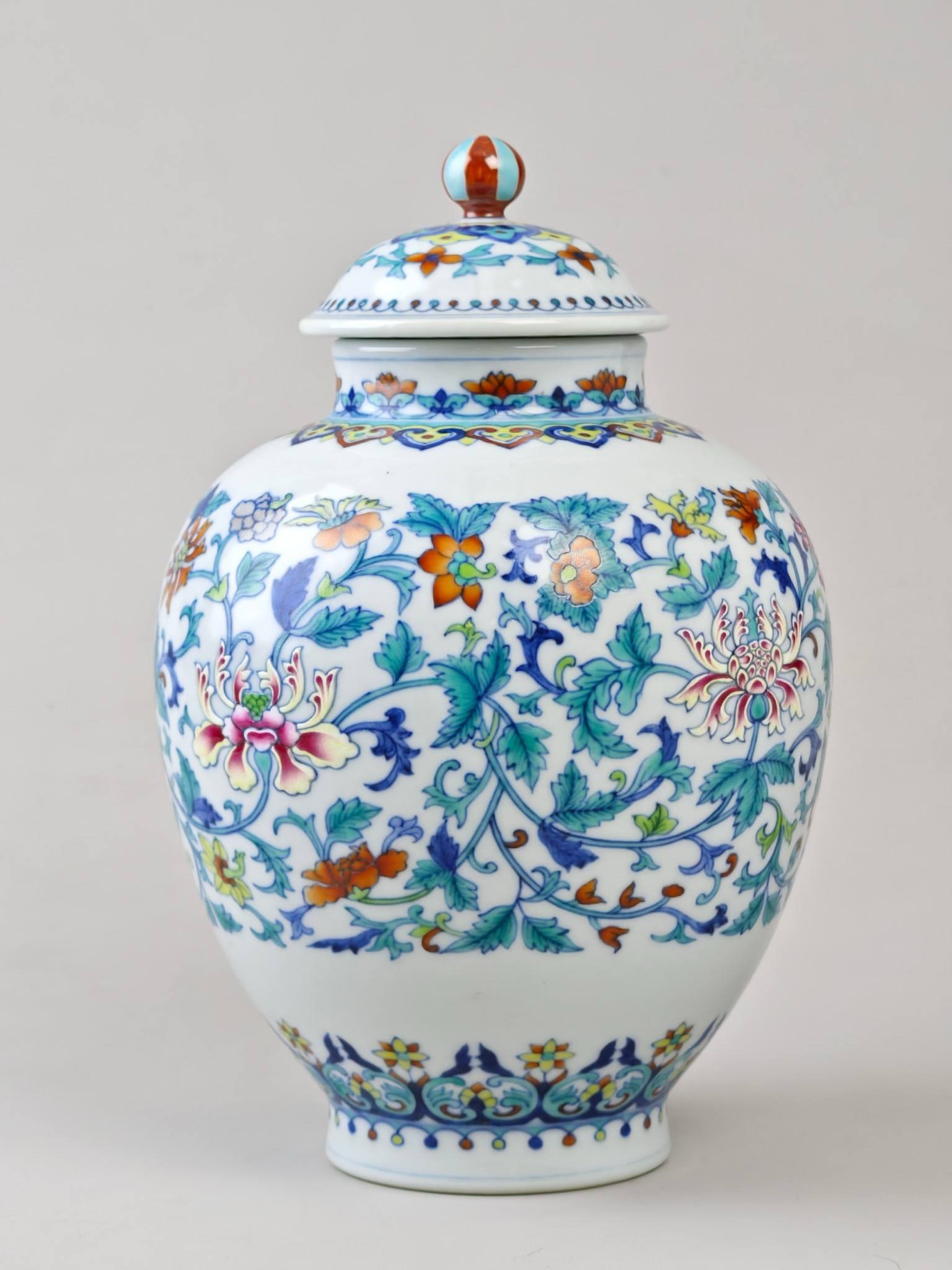 A doucai covered jar with lotus scroll design: A doucai covered jar with lotus scroll design, made during the Qianlong period of the Qing Dynasty. Height: 25 cm, Diameter: 17 cm.