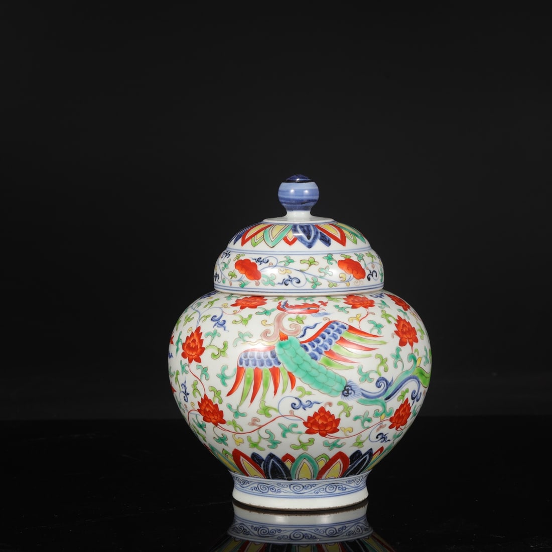 A large covered jar with blue and white porcelain and polychrome phoenix scroll design from the: Dimensions: Height 28.5 cm, Mouth diameter 11 cm, Belly diameter 21.5 cm.