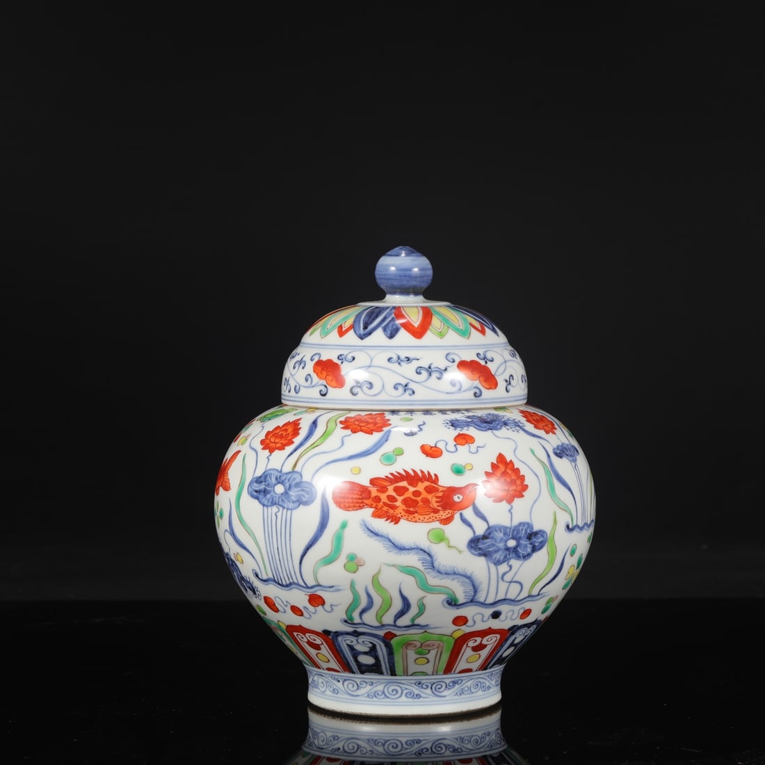 A large covered jar with blue and white porcelain and polychrome fish and algae design from the: Dimensions: Height 28 cm, Mouth diameter 11.5 cm, Belly diameter 22 cm.