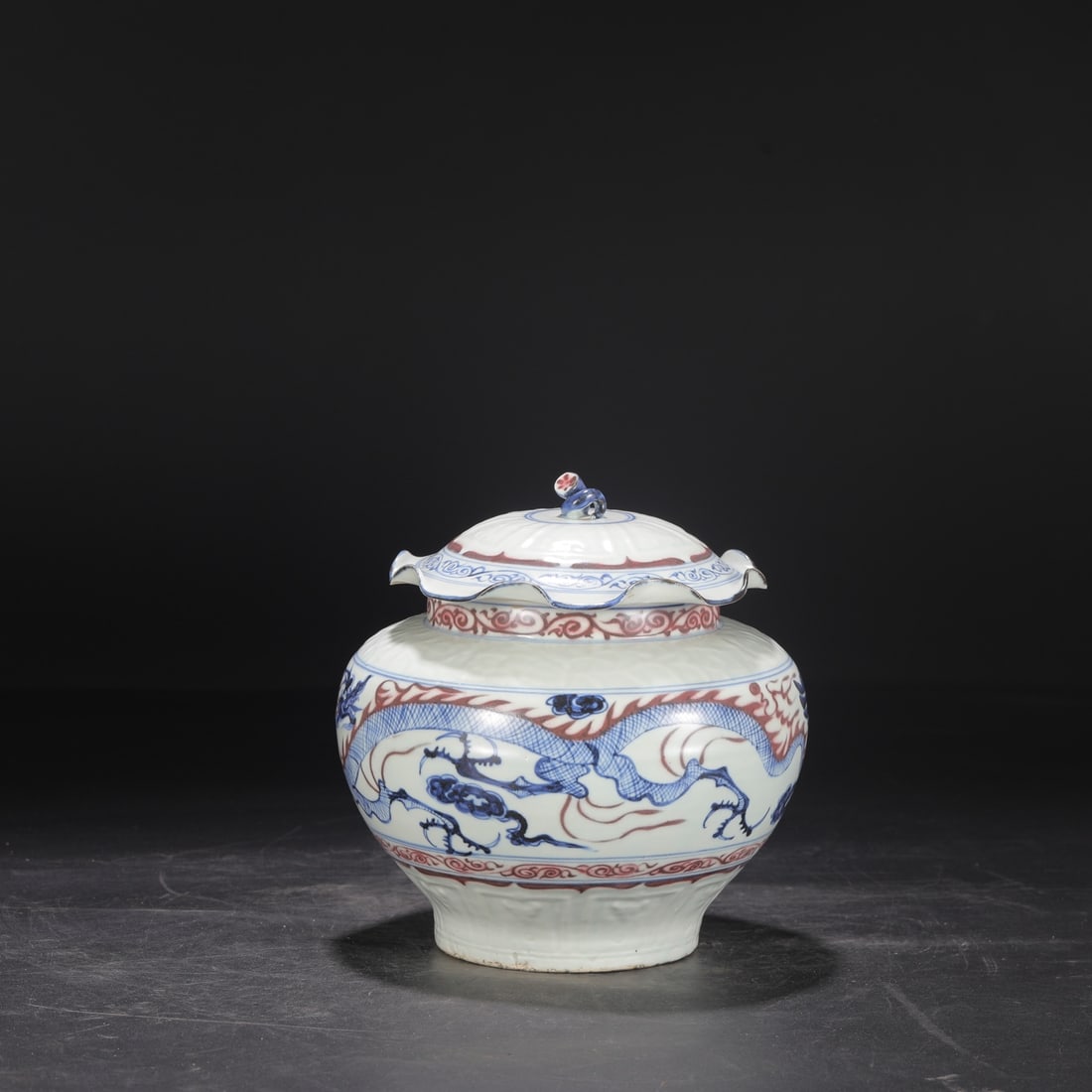 A Yuan Dynasty blue-and-white underglaze red dragon and phoenix lotus leaf covered jar, formerly in: Height: 21.5 cm, Mouth diameter: 13 cm, Belly diameter: 20 cm
