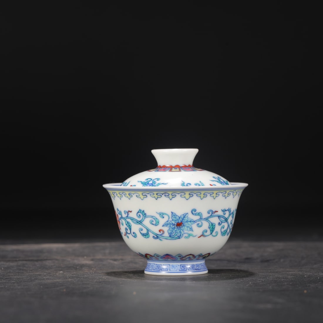 A Qing Dynasty Yongzheng period doucai tea bowl with a covered lid and a design of intertwined: Dimensions: Height 7 cm, Diameter 8.5 cm.