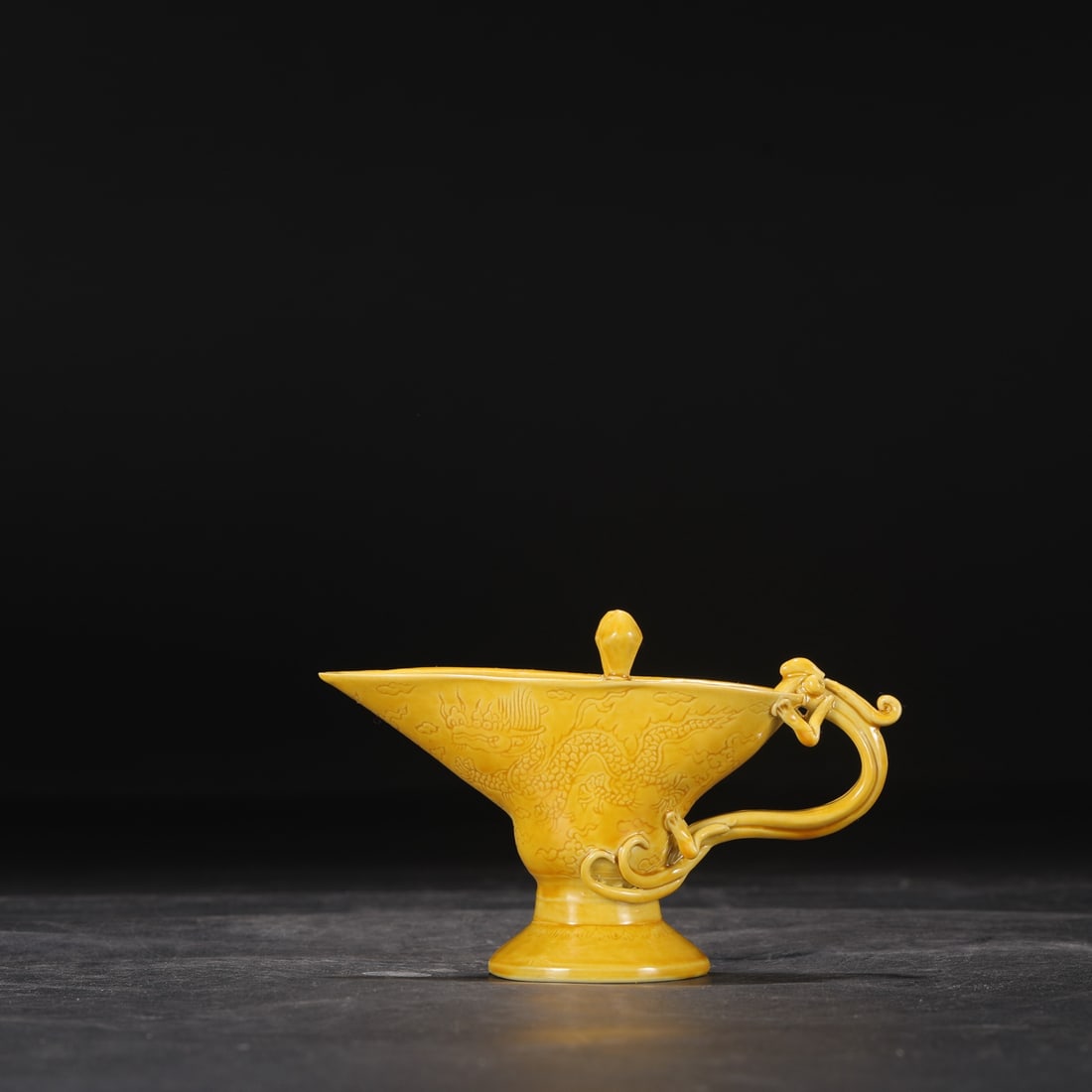 A Ming Dynasty Hongzhi period pale yellow glazed wine cup with incised cloud and dragon design.: Dimensions: Height 9.5 cm, Mouth diameter 11.5 cm.