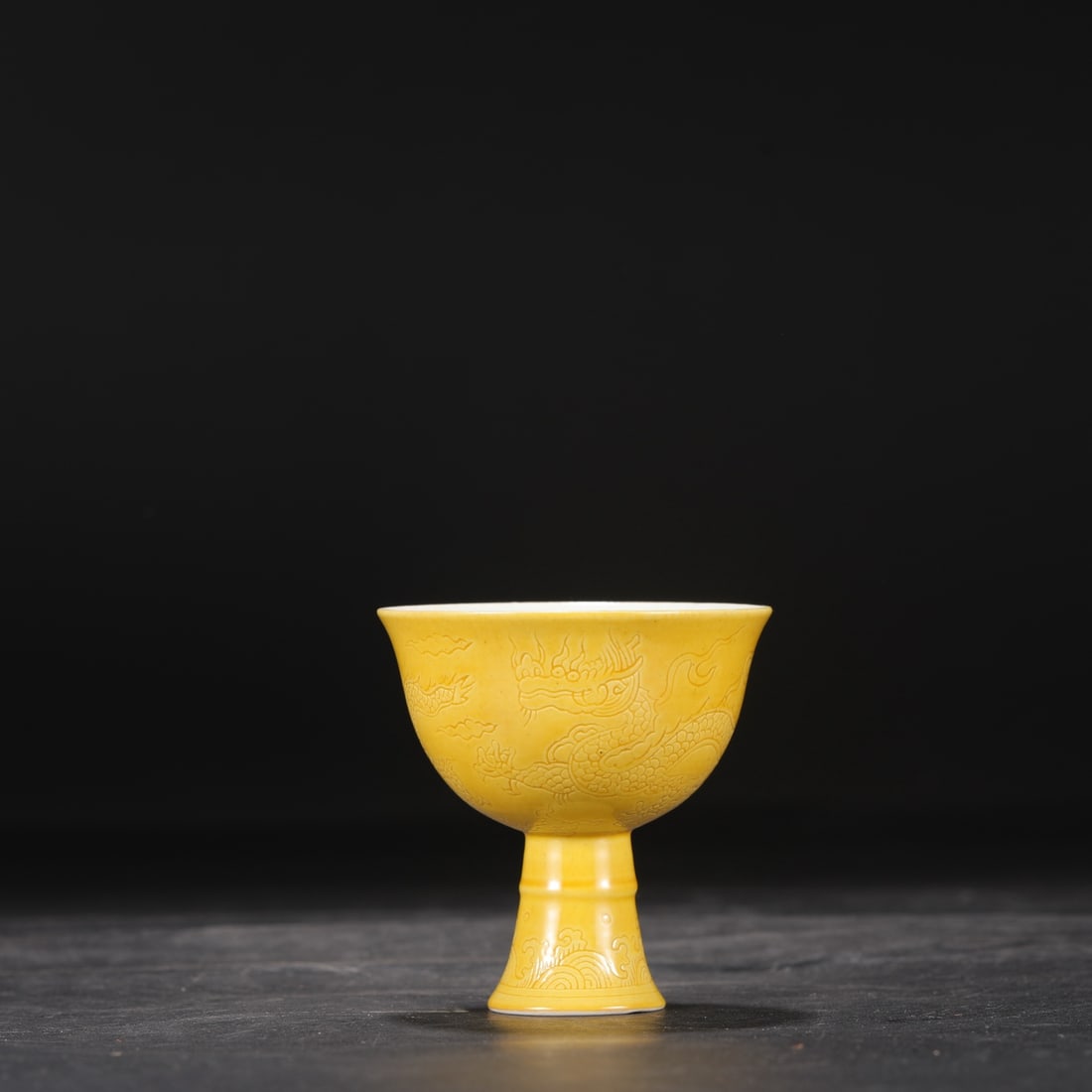 A Ming Dynasty Chenghua period stem cup with a delicate yellow glaze and incised cloud and dragon: Dimensions: Height 8.8 cm, Mouth Diameter 8.5 cm.